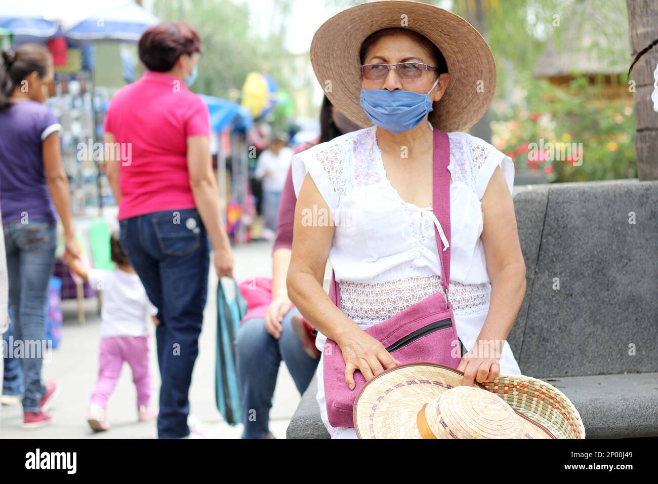 Ältere Erwachsene Frau mit Schutzmaske und Hut im öffentlichen Garten mit Hut, neuer normaler Covid-19 Stockfoto