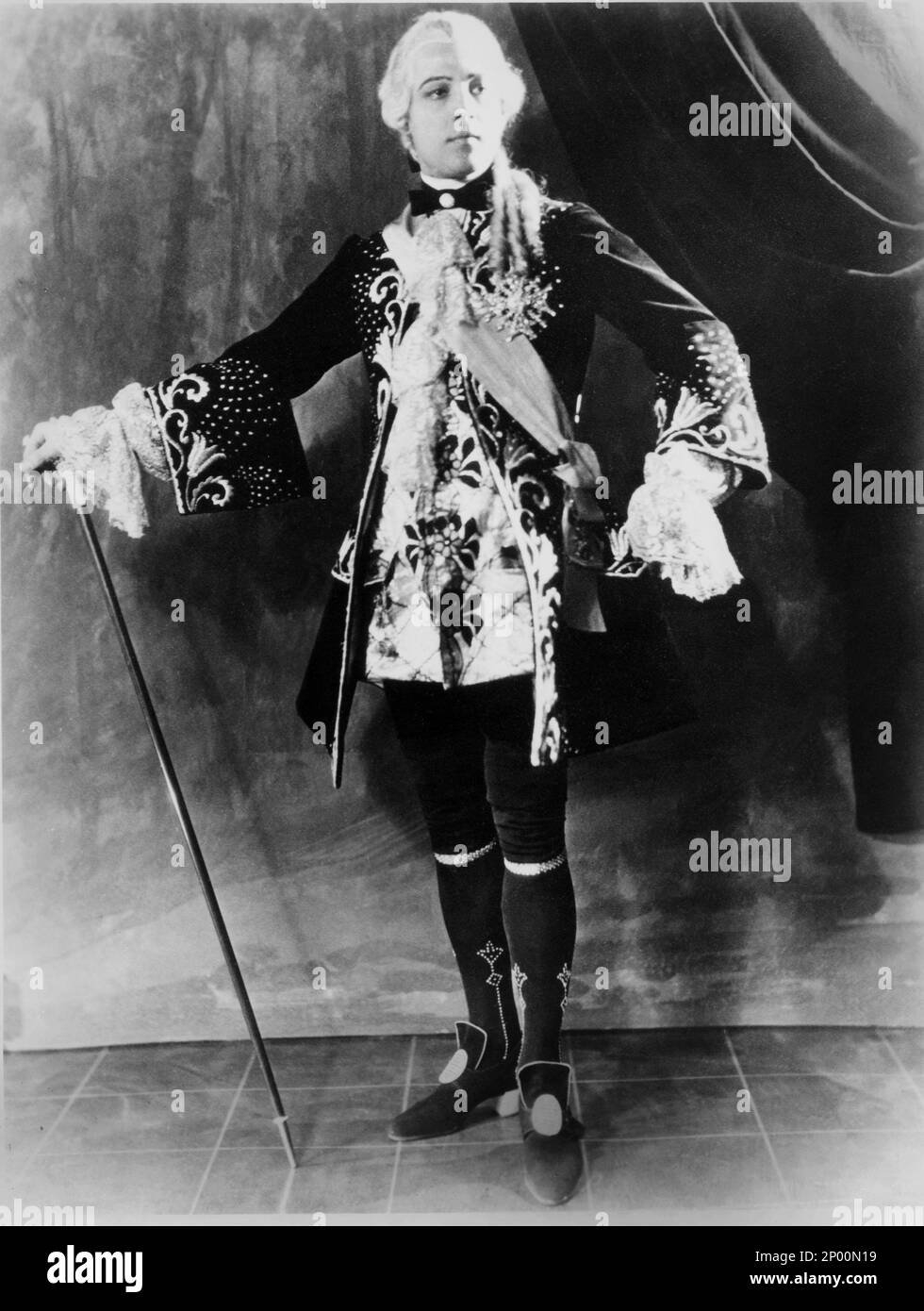1924 , Vereinigte Staaten : der Stummfilmdarsteller RUDOLPH VALENTINO ( geboren Rodolfo Guglielmi , 1895 - 1926 ), Probeaufnahme FÜR MONSIEUR BEAUCAIRE von Sydney Olcott , aus dem Roman von Booth Tarkington , Kostüm von George Barbier - CINEMA MUTO - RODOLFO - attore cinematografico - Bastone da passeggio - Skipe - Schuhe - Stivali - Kragen - colletto - LATEINAMERIKANISCHER LIEBHABER - italoamericano - italo-americano - Emigrant - emigrante - italo-american - Portrait - Rituca - Parperücke - pizzo - Spitze - Rouches --- Archivio GBB Stockfoto