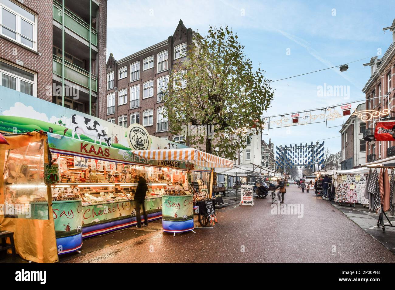 Amsterdam, Niederlande - 10. April 2021: Ein Food Truck, der am Straßenrand geparkt ist, mit Menschen, die um ihn herum laufen, und Gebäuden in der Ferne dahinter Stockfoto