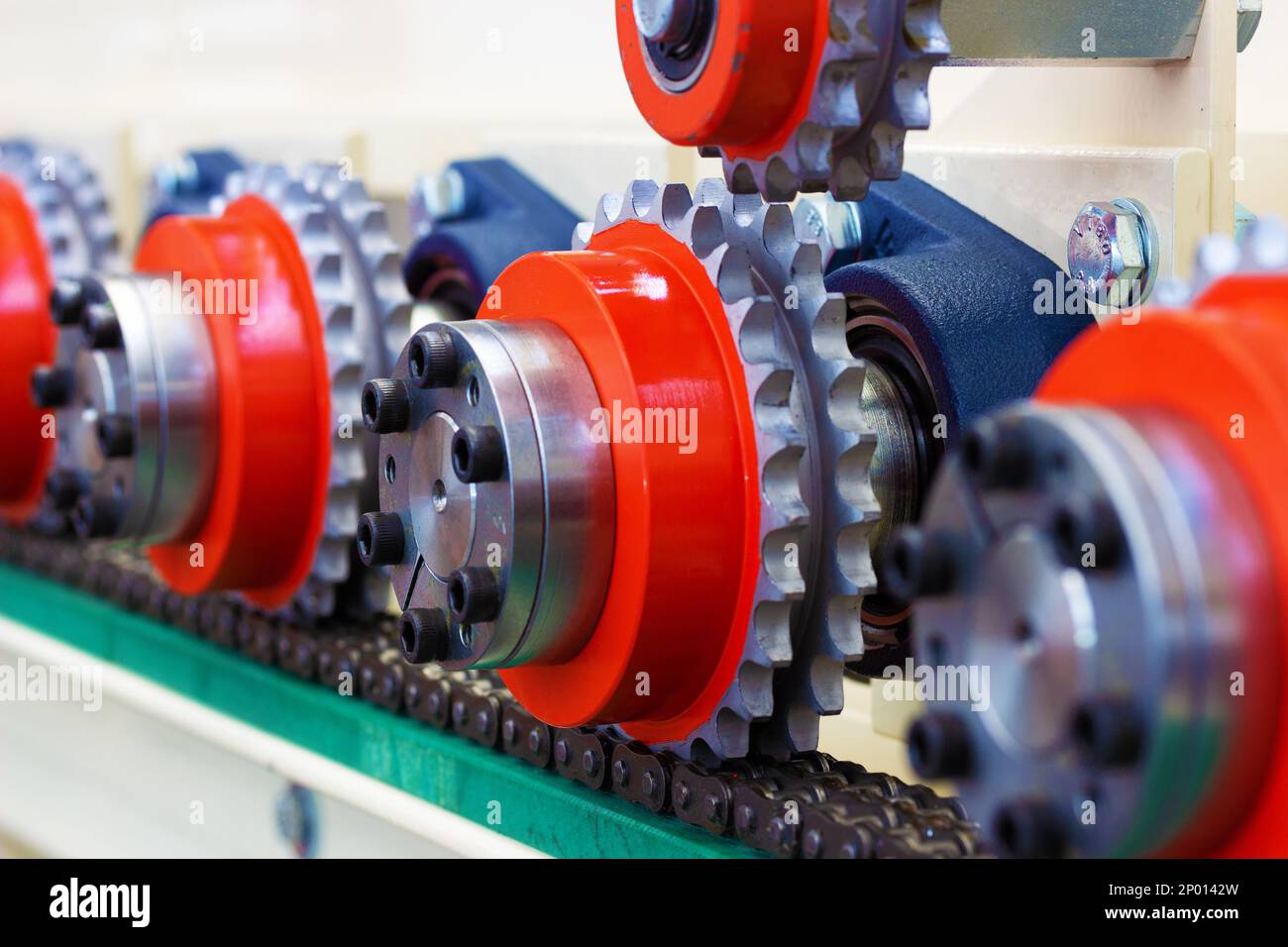 Details von bunten Zahnrädern, Riemenscheiben und einer Zugkette einer Industriemaschine Stockfoto