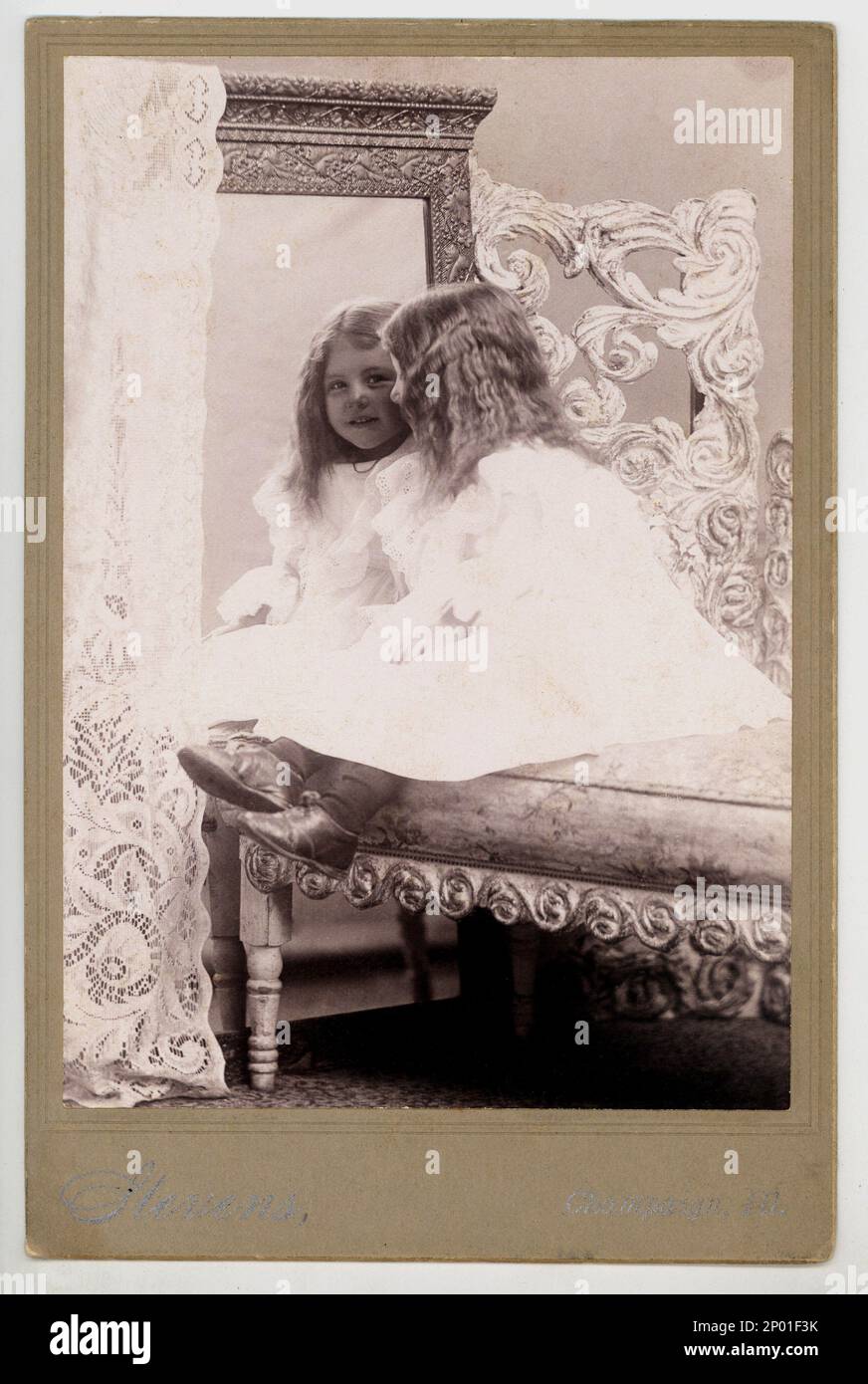 1899 , Champaign , Illinois , USA : Ein kleines Mädchen im Spiegel - Bambina - Infantin - bambino - Kind - Kinder - BELLE EPOQUE - Età VITTORIANA - VIKTORIANER - SPECCHIO - riflesso - Reflex - Lächeln - sorriso - Schuhe - Schal - pizzo - Spitze - weißes Kleid - Abito bianco - MODE - FOTO di MODA - divano - sofà - Couch Babys - Baby ----- Archivio GBB Stockfoto