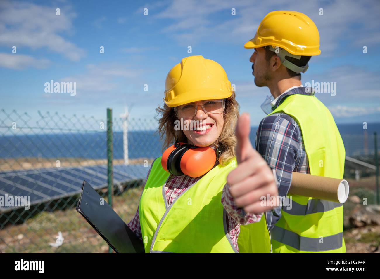 Glückliche Ingenieurin zeigt Daumen nach oben auf der Solarfarm. Stockfoto