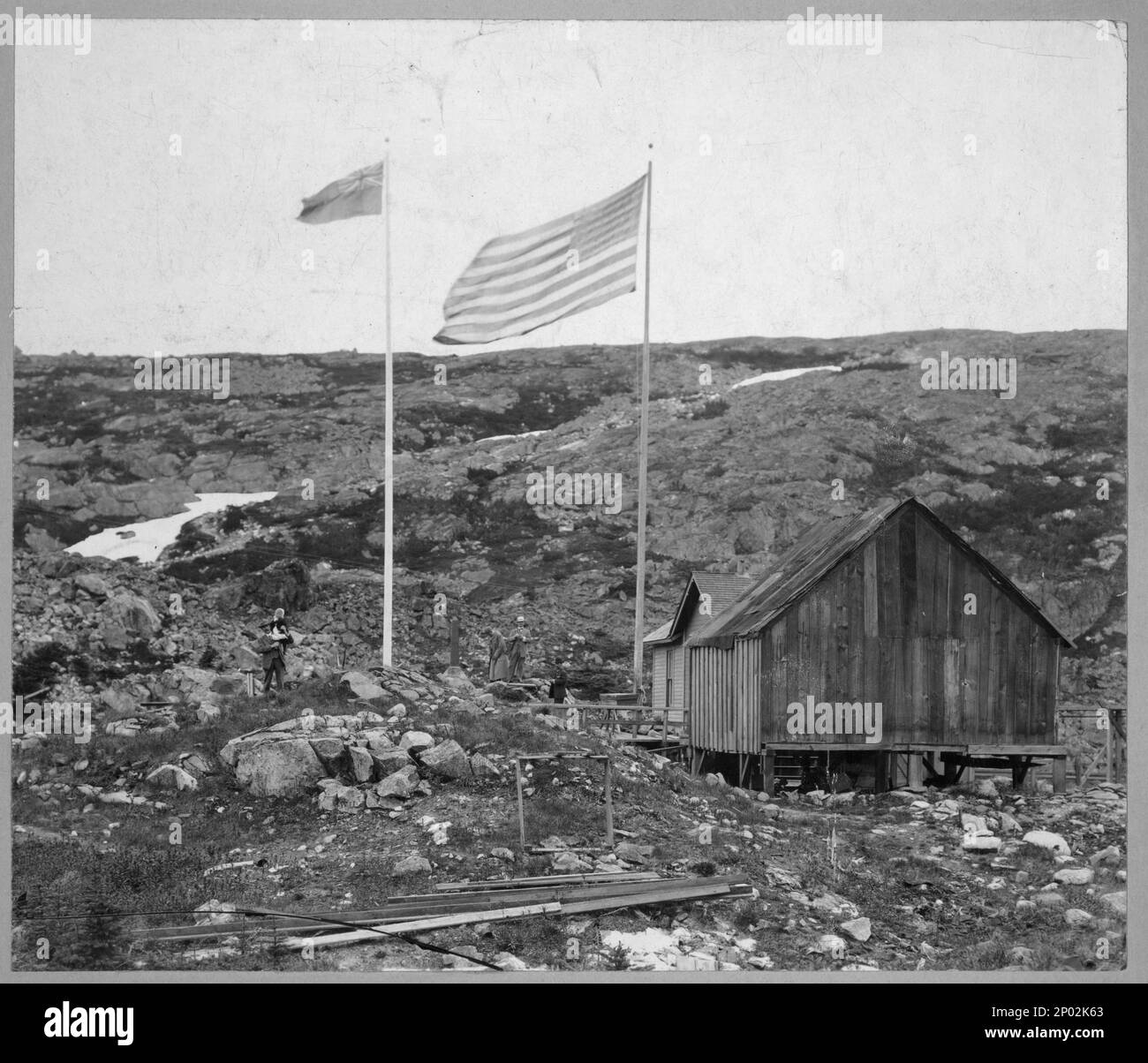 Alaska - Grenze Yukon. Frank and Frances Carpenter Collection , Gift; Mrs. W. Chapin Huntington; 1951, Dwellings,Canada,1890-1930, Dwellings,Alaska,1890-1930, Flags,Canadian,1890-1930, Flaggen,Amerikanisch,1890-1930, Grenzen,Kanada,1890-1930, Grenzen,Alaska,1890-1930, Felsen,Kanada,1890-1930, Felsen,Alaska,1890-1930, Usa, Alaska Stockfoto