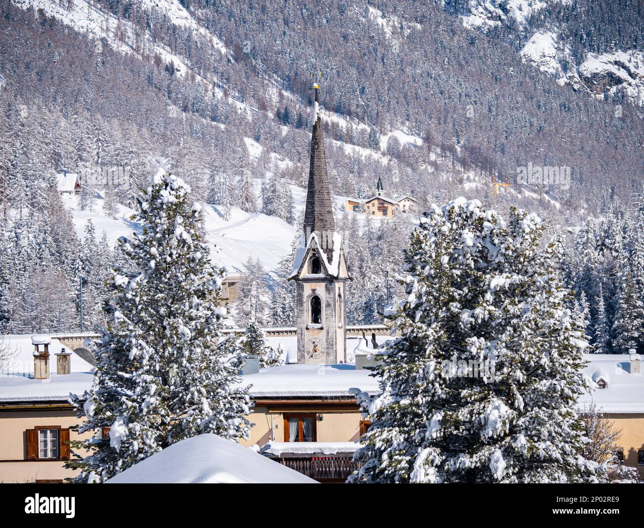 Winterblick auf einem Glockenturm einer reformierten Kirche in einem schneebedeckten Dorf Cinuos Chel in Engadine, Grisons, Schweiz. Stockfoto