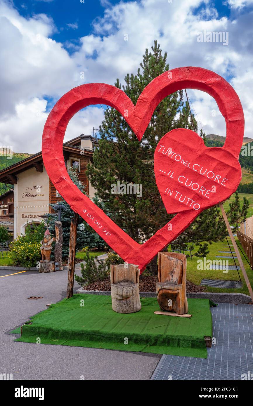 Livigno, Italien - 29. September 2021: Ein großes künstliches rotes Herz mit Inschrift in englischer Übersetzung: Alles ist im Herzen... Ein Herz ist in E Stockfoto