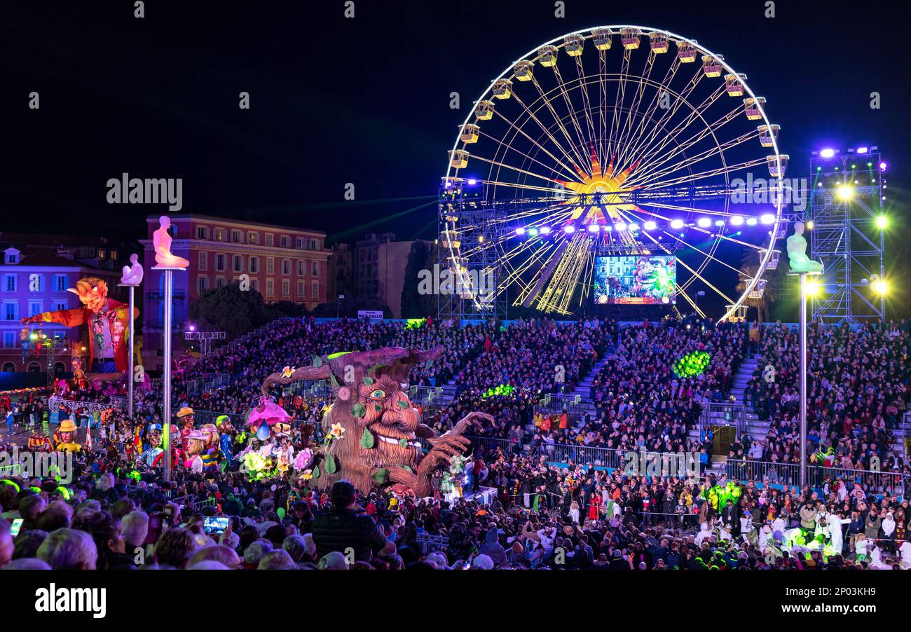 Gleiten Sie bei Nacht (Mutter Erde) auf der 150. Jährlichen Karnevalsparade der Lichter in Nizza. Großes Riesenrad im Hintergrund. Stockfoto