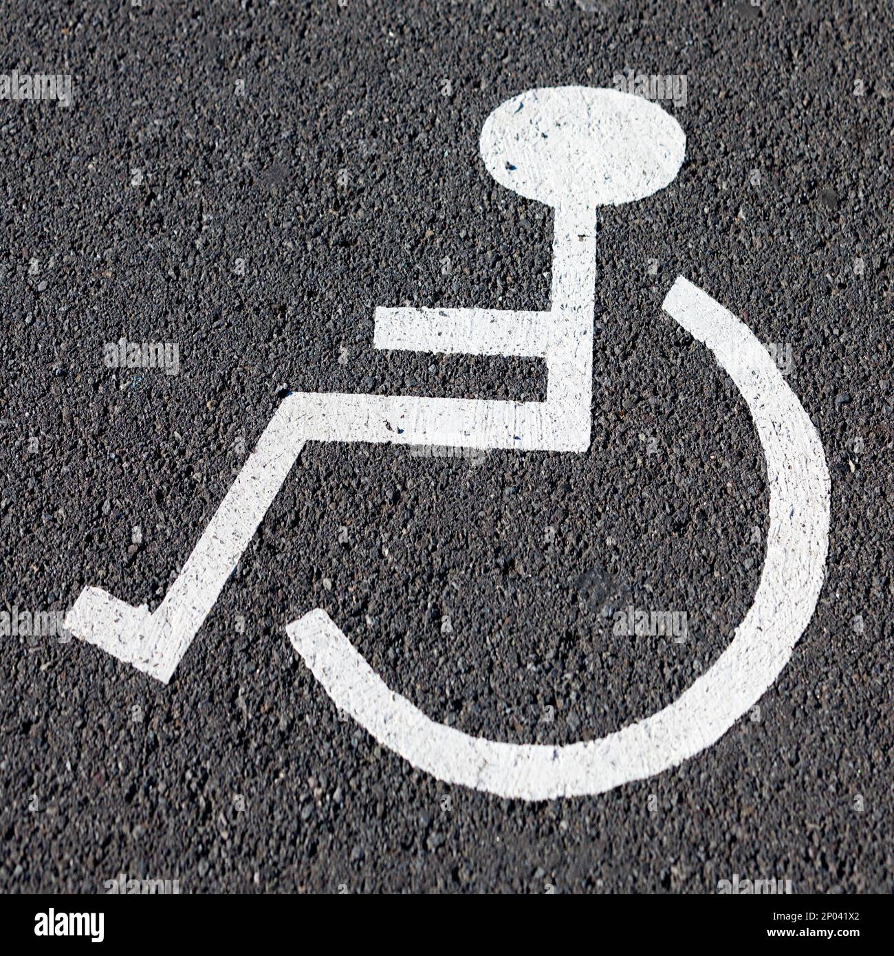 Nahaufnahme eines weißen Behindertenparkschilds auf dem Asphalt. Stockfoto