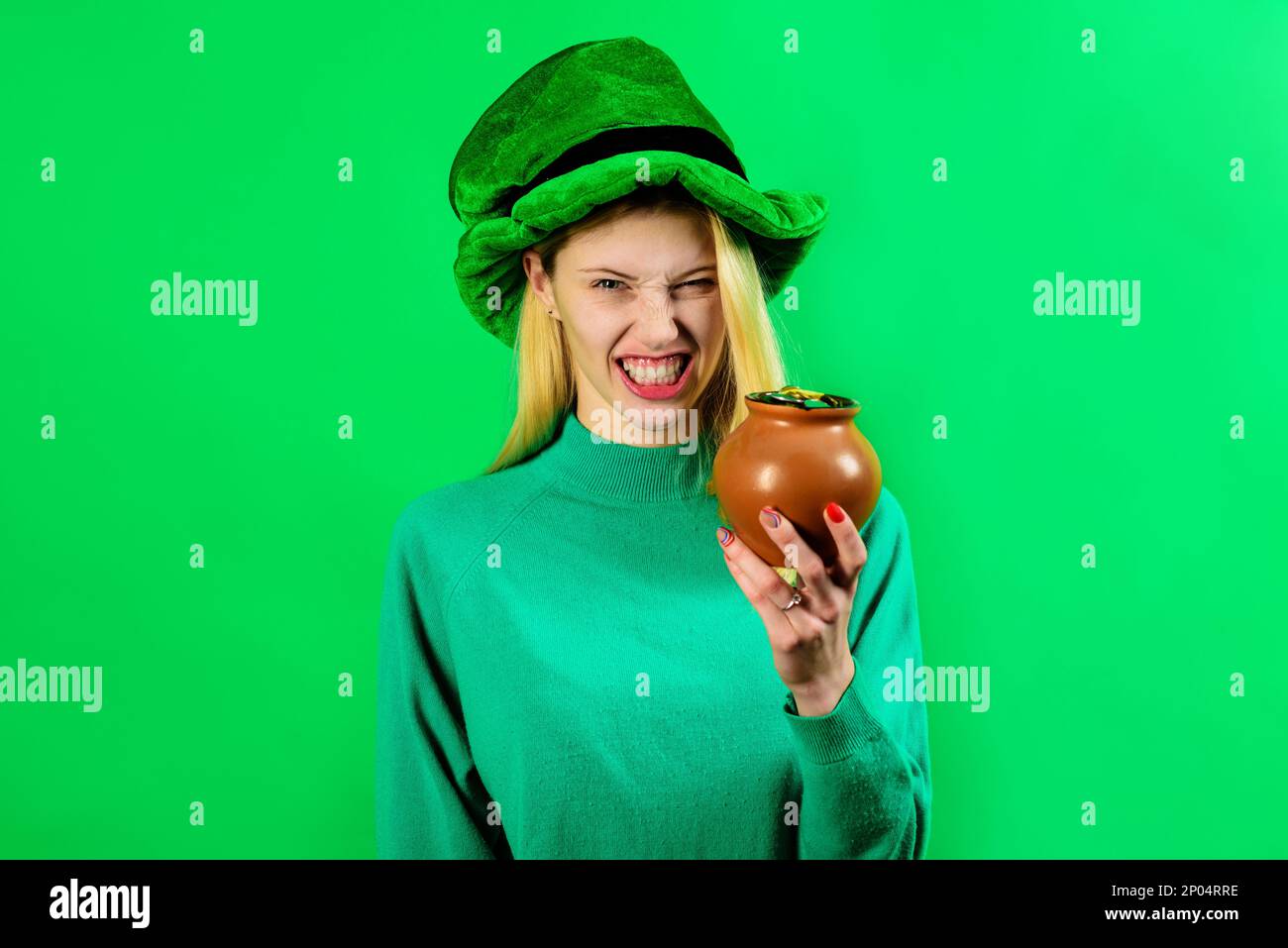St. Patrick's Day. Irische Traditionen. Wütendes blondes Mädchen mit grünem Leprechaun-Hut und einem Topf Gold. St. Patrick Day Frau mit einem Haufen Geld. Weiblich Stockfoto