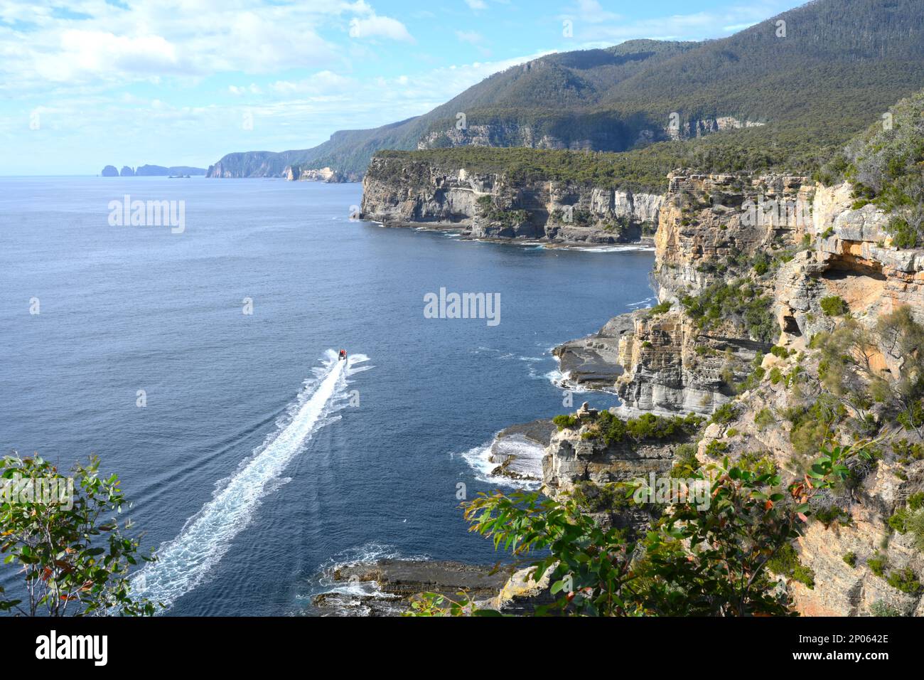 Ein Boot fährt über den Ozean unter den riesigen Klippen und Landzungen von Cape Hauy, Tasmanien, Australien Stockfoto