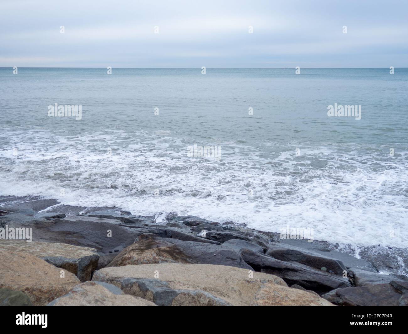 Die felsige Küste wird bei bewölktem Wetter von den Wellen gewaschen. Schwarzmeerküste. Die Küste von Batumi. Natur in Grautönen. Grau. Langweilige Landschaft Stockfoto