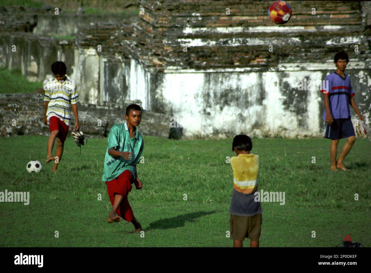 Kinder spielen Fußball auf einem Grasfeld zwischen den Ruinen des Kaibon Palace, einem kulturellen Erbe der Banten Sultanate-Zeit, das sich in einer Gegend namens Banten Lama (Old Banten) in Serang, Banten, Indonesien befindet, auf diesem Foto, das 2004 aufgenommen wurde. Eine kürzlich von Nurikah und E. Rakhmat Jazuli (Fakultät für Recht, Sultan Ageng Tirtayasa Universität, Banten) durchgeführte Feldforschung hat ergeben, dass es zahlreiche Verstöße gegen die Behandlung von Kulturerbeobjekten in der Region gab. Die Menschen üben sportliche Aktivitäten in der Umgebung von Kulturerbeobjekten aus, zum Beispiel Fußball spielen auf... Stockfoto