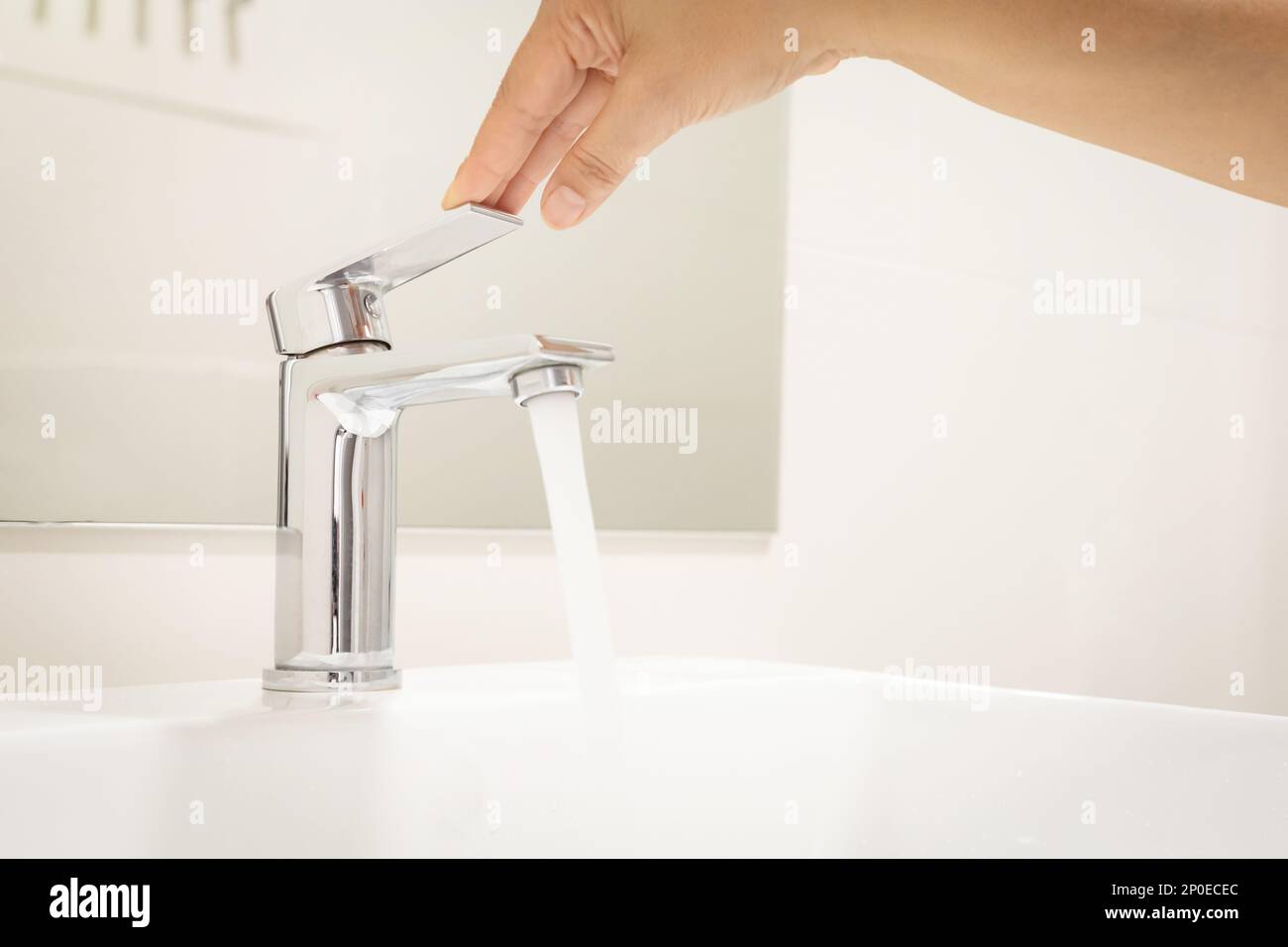 Schließen Frau öffnen Pull Chrom Wasserhahn Waschbecken zum Waschen Hand Seife für Corona Virus am Wasserhahn. Den fließenden Wassertropfen abdrücken. Badezimmer Stockfoto