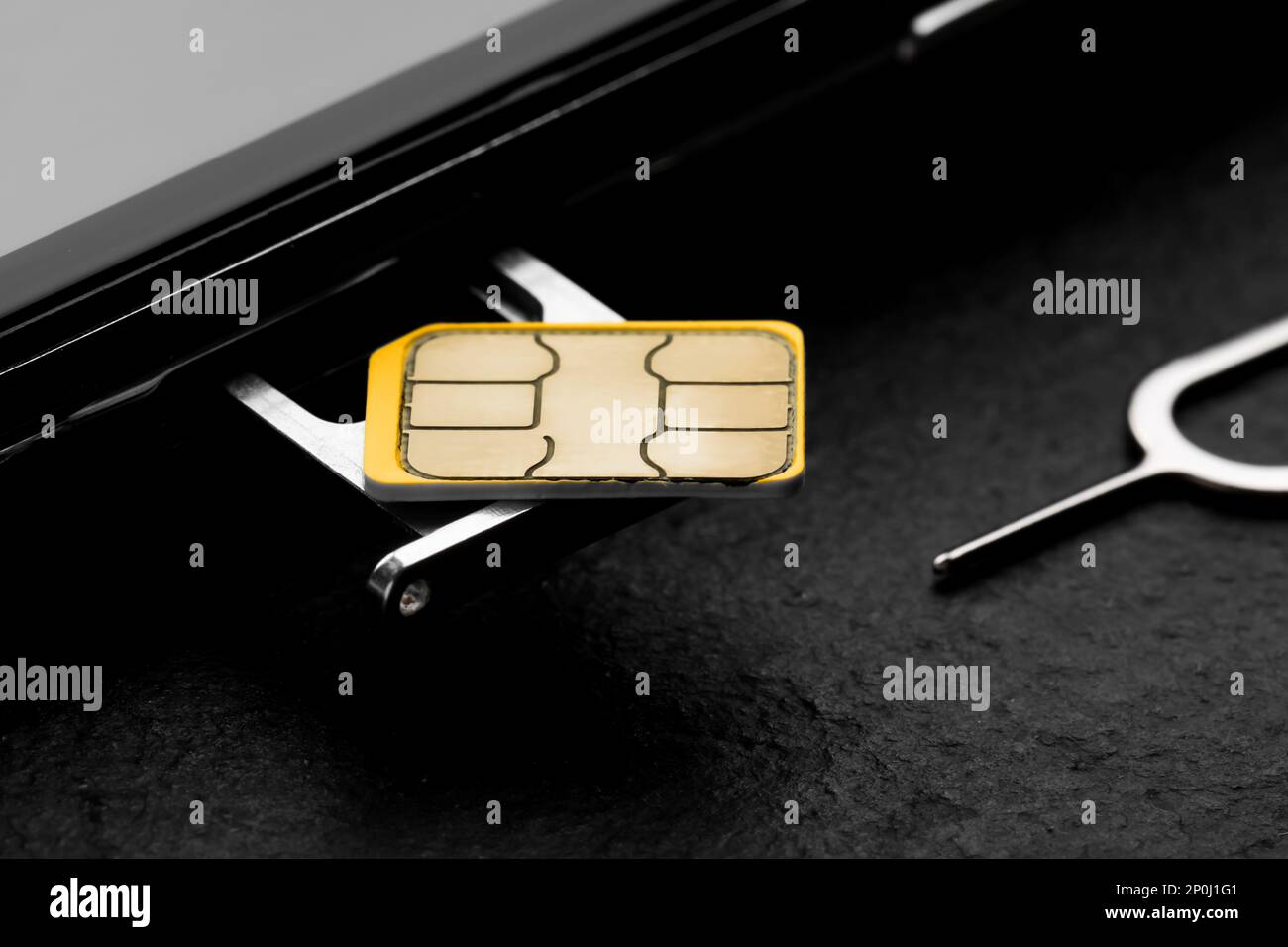 SIM-Karte, Mobiltelefon und Auswerfer auf schwarzem Tisch, Nahaufnahme Stockfoto