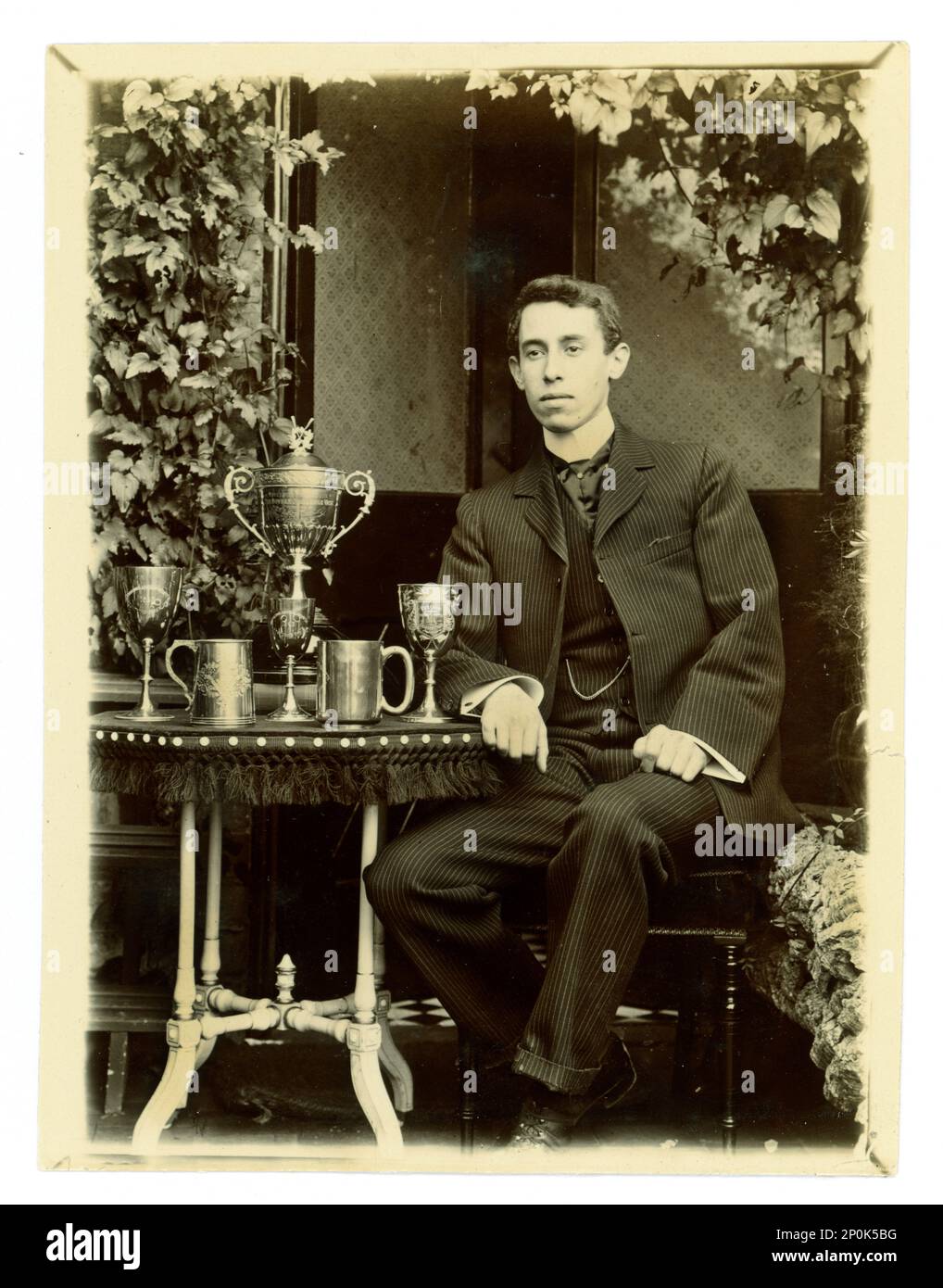 Original-viktorianisches Foto von Gent, auf einem Tisch ist eine große Worcester Challenge Vase,/Regatta-Trophäe zum Rudern und andere Tassen, möglicherweise Mitglied einer gefrästen vier Crew. Worcester Gegend, Großbritannien, ca. 1897-1899 Stockfoto