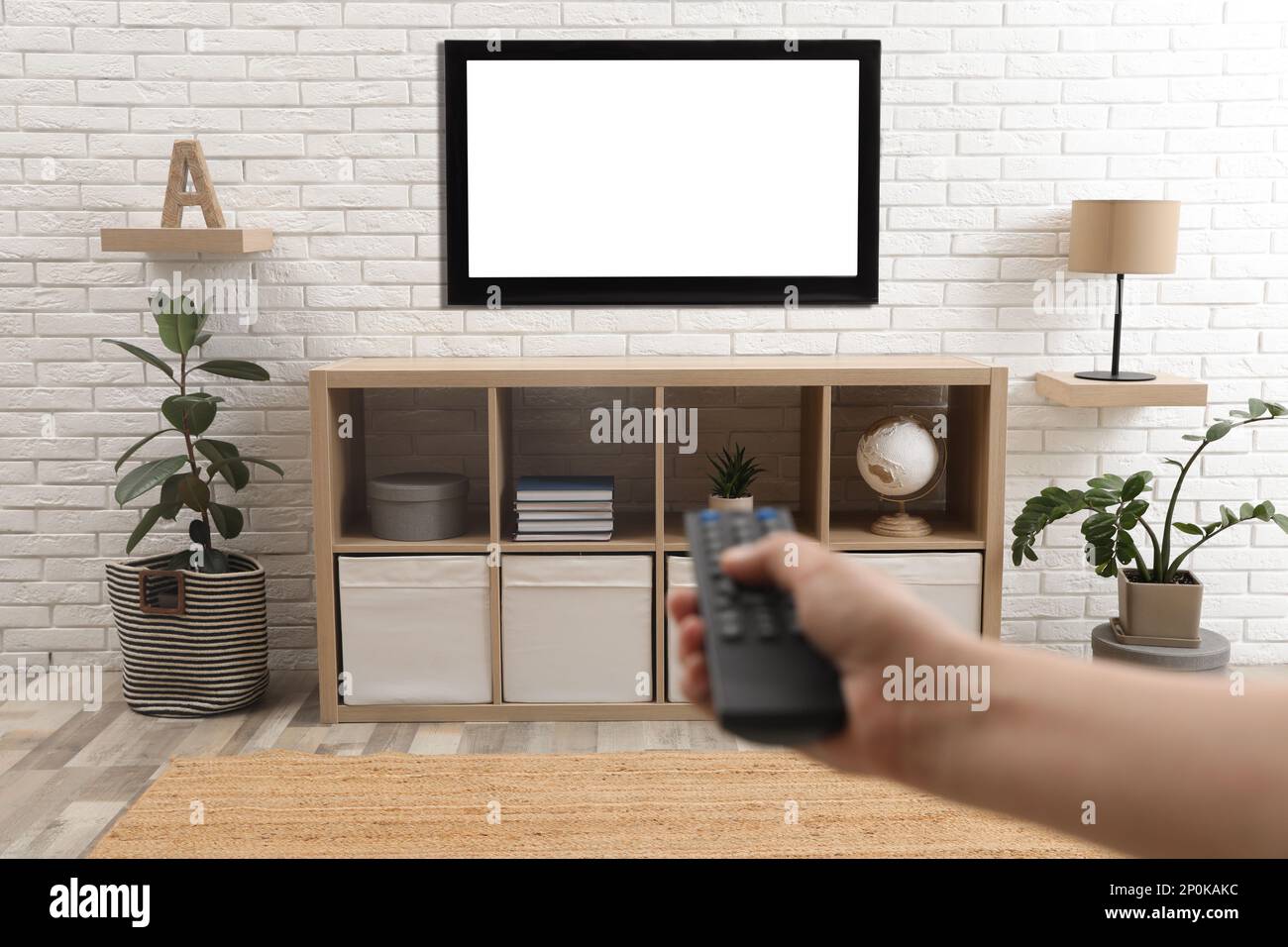 Ein junger Mann, der zu Hause mit Fernbedienung die Sender umschaltet, Nahaufnahme Stockfoto