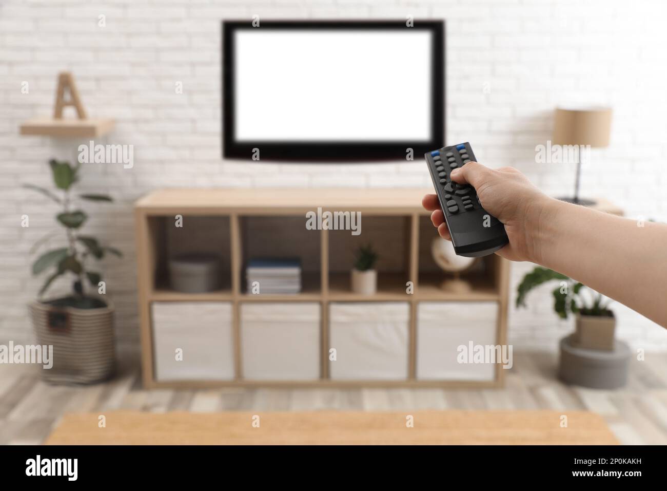 Ein junger Mann, der zu Hause mit Fernbedienung die Sender umschaltet, Nahaufnahme Stockfoto