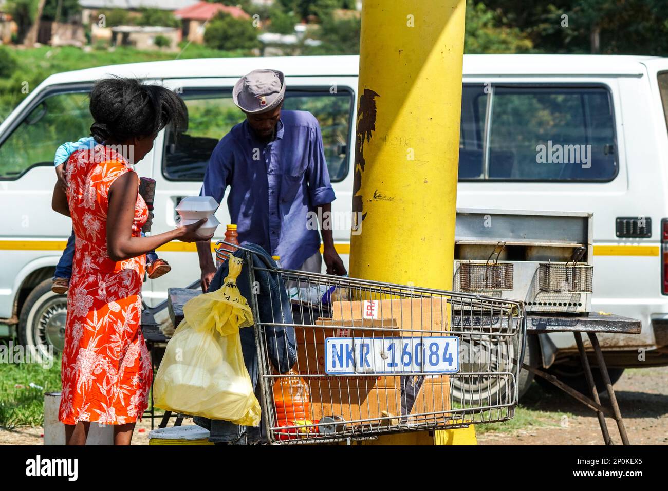 Afrikanischer Straßenverkäufer für kleine Unternehmen, der einem Kunden Essen zum Mitnehmen an einem Straßenrand in Kwazulu Natal, Südafrika, verkauft Stockfoto
