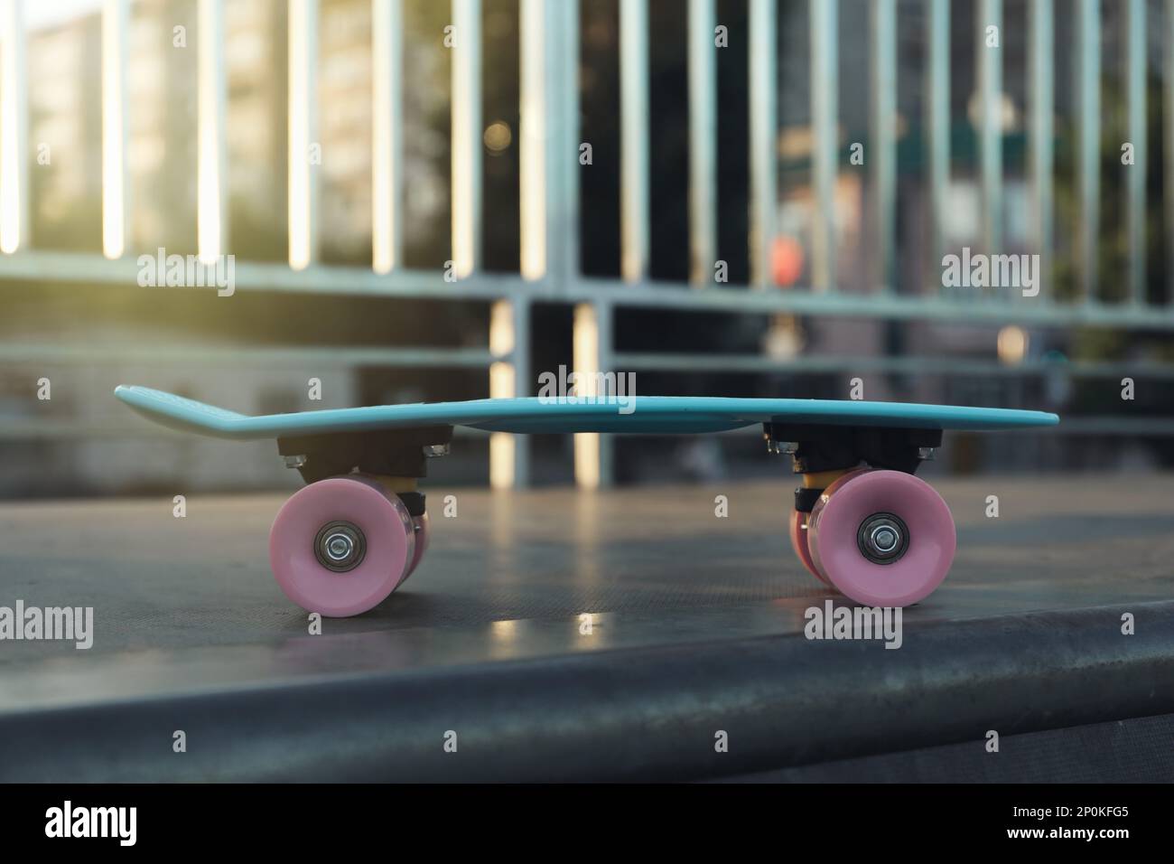 Modernes hellblaues Skateboard mit pinkfarbenen Rädern oben auf der Rampe im Freien Stockfoto