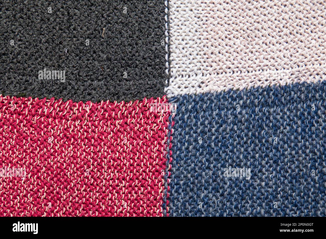 Traditioneller Strickhintergrund. Wollgestricktuch in Weiß, Schwarz, Blau und Rot Stockfoto