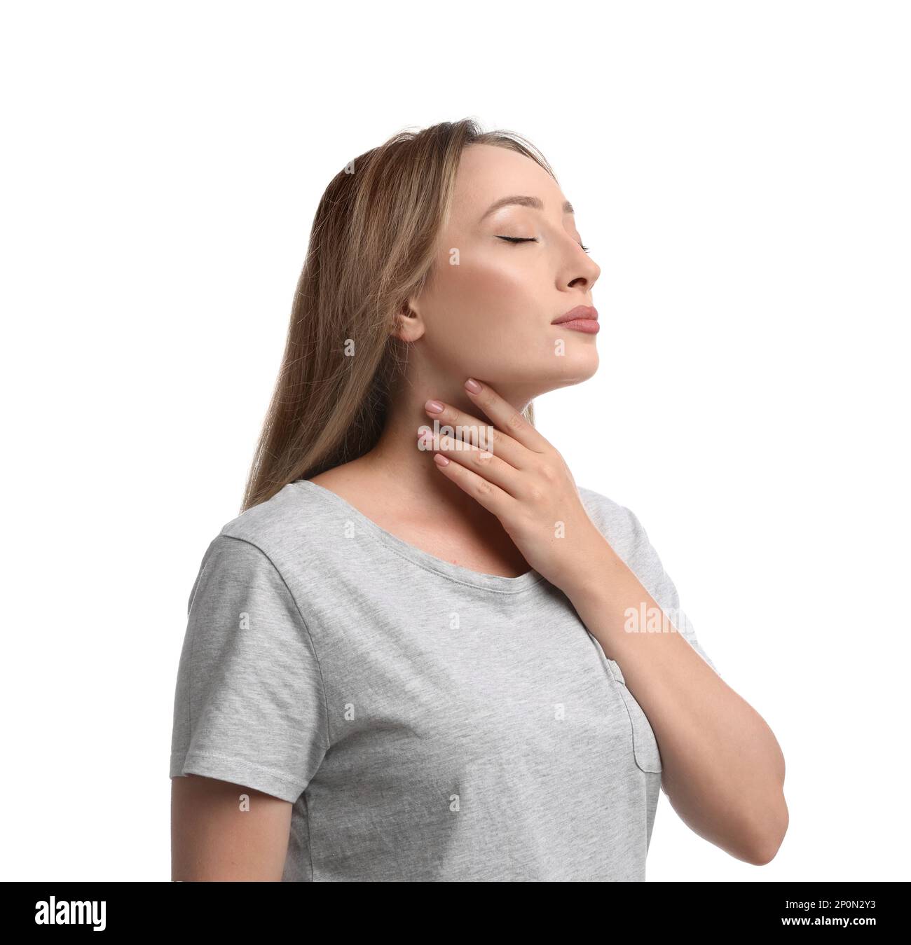 Junge Frau, die Schilddrüsen-Selbstuntersuchung auf weißem Hintergrund macht Stockfoto