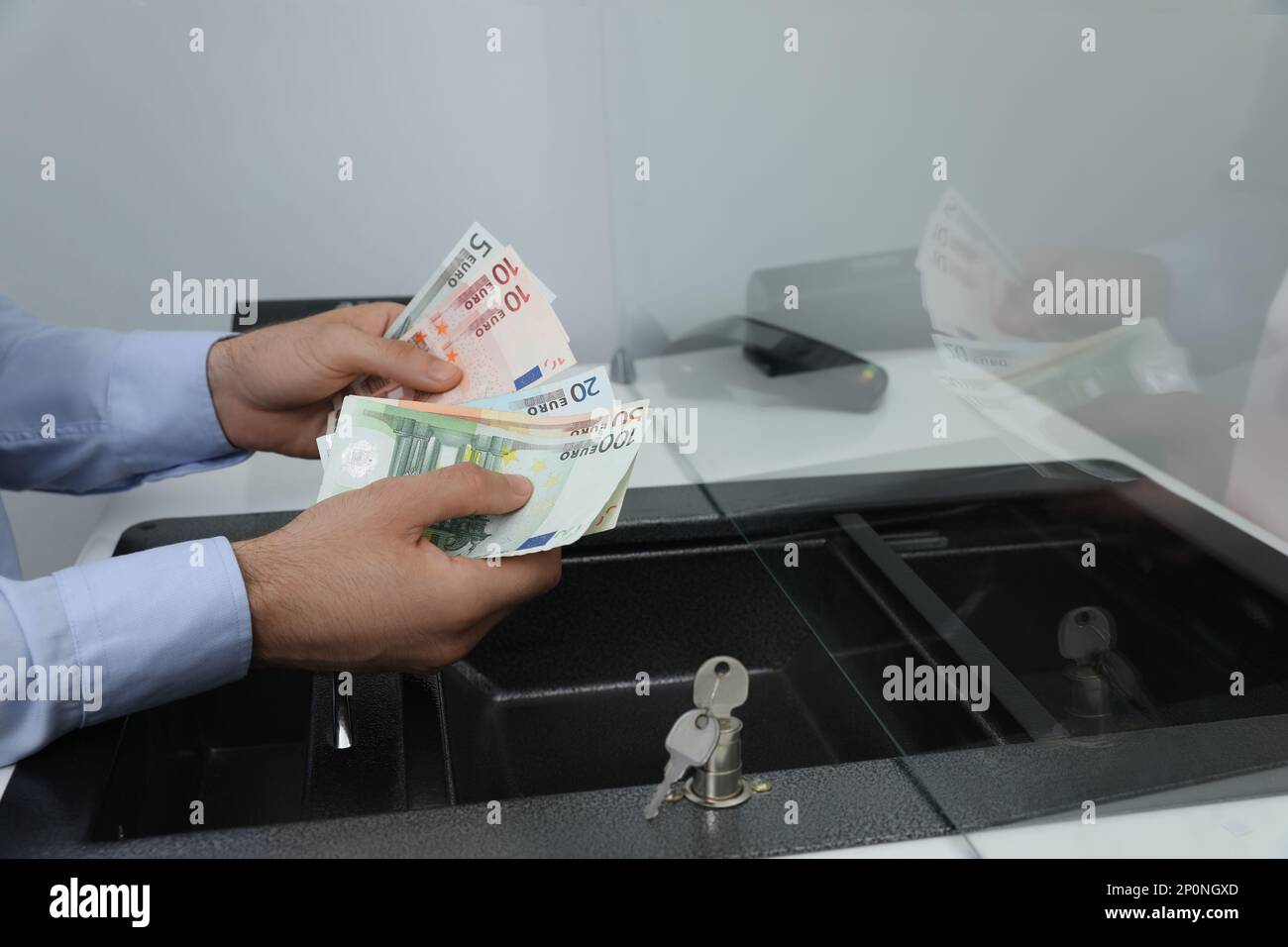 Kassierer mit Geld am Fenster der Währungsabteilung in der Bank, Schließung Stockfoto