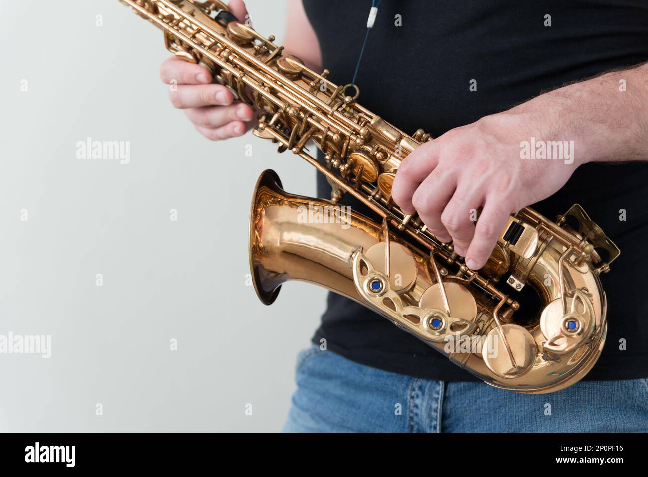 Ein Mann in schwarzem Hemd hält Saxophon. Horizontales Foto des Musikers mit Kopierbereich Stockfoto