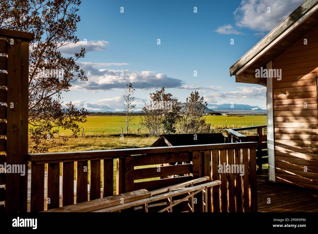 Isländisches Chalet mit Terrassenbalkon in Selfoss, umgeben von wunderschöner Landschaft, mit dem Fluss Olfusa in der Ferne. Schöner blauer Himmel Stockfoto