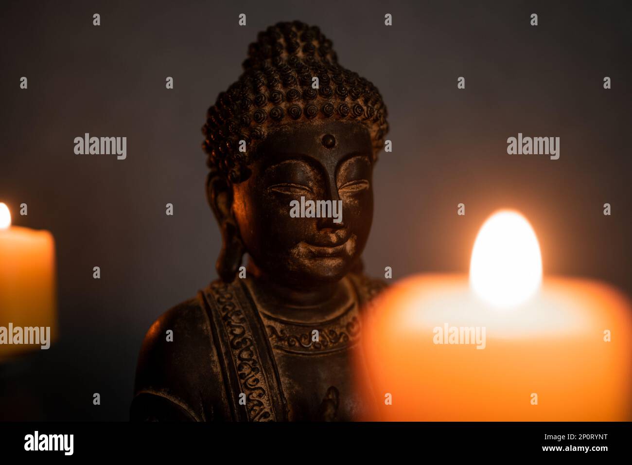 Buddha-Statue mit selektivem Fokus und verschwommenen Kerzen, die in dunkler Umgebung brennen. Buddhismus-Konzept Stockfoto