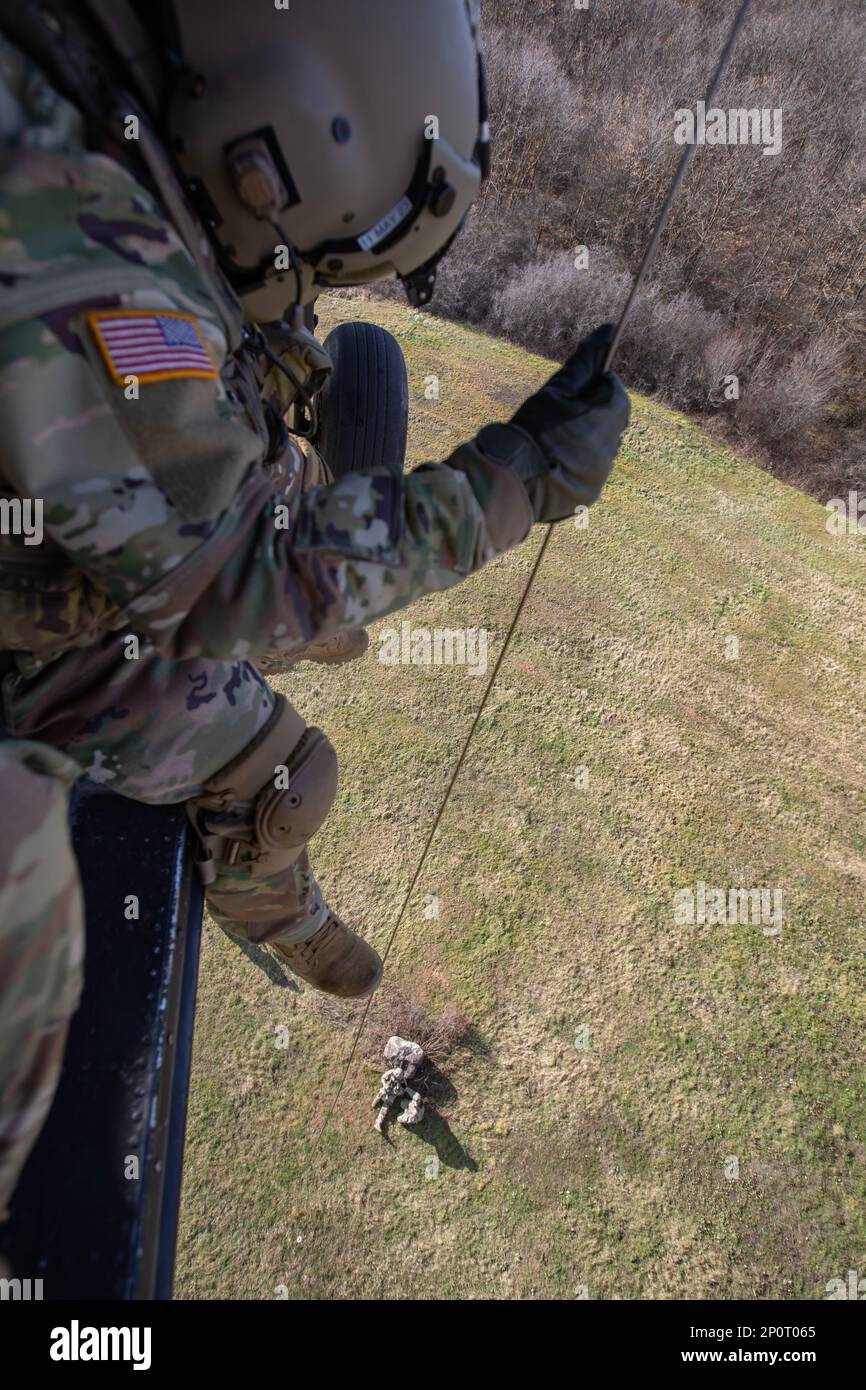 Sgt. 1. Klasse Jonas Chinea erhebt Sergeant 1. Klasse Anthony Bonillas, Kosovo Force (KFOR) Regional Command-East (RC-E) Soldaten mit der medizinischen Evakuierungseinheit, die Charlie Company zugewiesen wurde, 2. Bataillon, 149. Luftfahrtregiment, während sie am 6. Januar eine Hebeoperation von einem UH-60 Black Hawk Helikopter in Camp Bondsteel, Kosovo, durchgeführt haben. 2023. Stockfoto