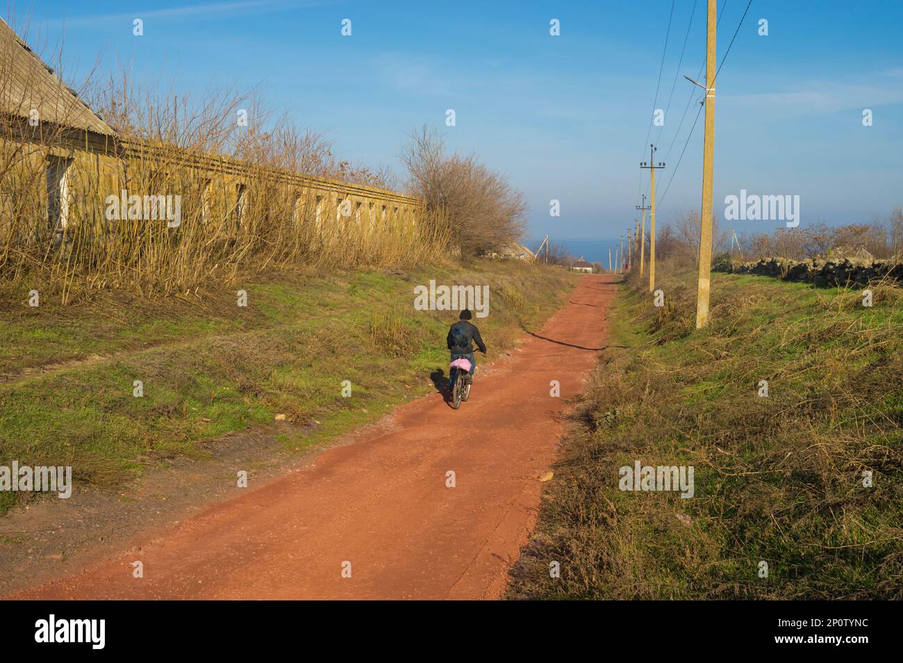 Landschaft mit roter Landstraße und Fahrrad im Dorf Skelky, Oblast Zaporizhzhia, Ukraine Stockfoto
