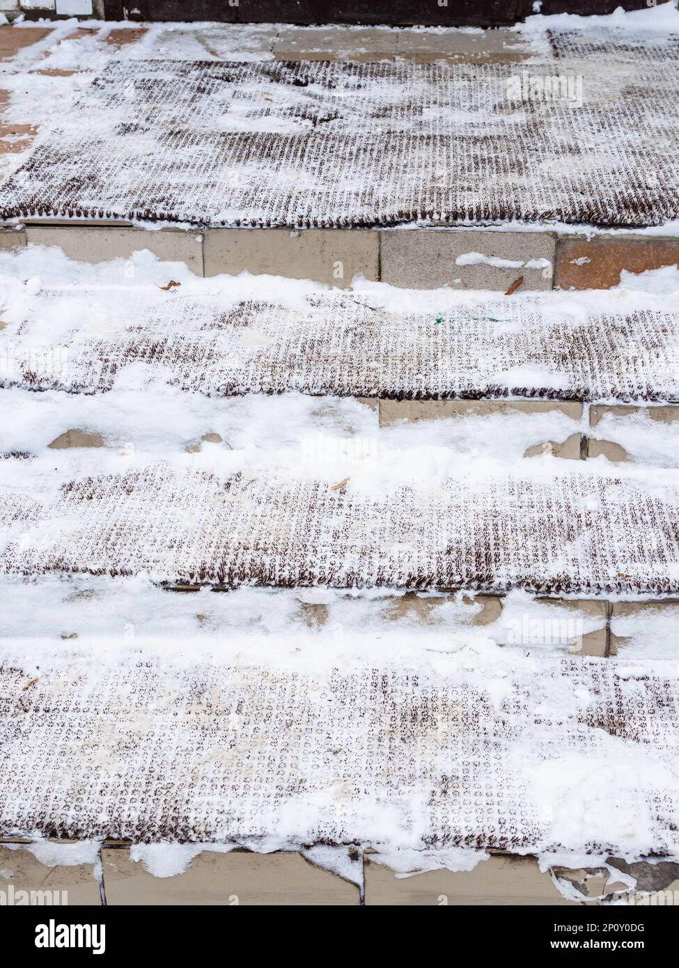 Schneebedeckte Türmatten auf den Stufen der Veranda des Stadthauses am Wintertag Stockfoto