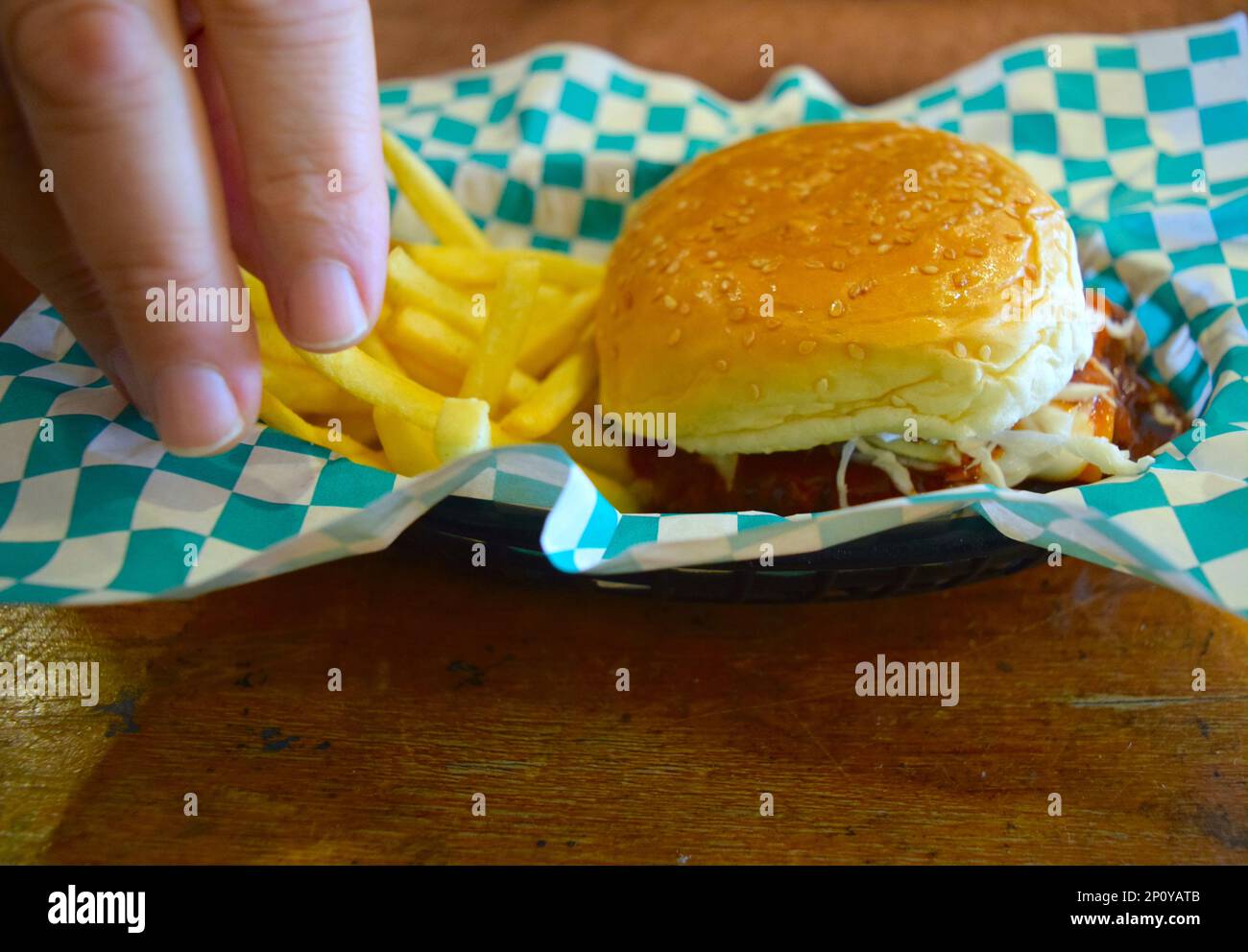 Die Person isst einen Fleischburger mit Pommes Frites. Stockfoto