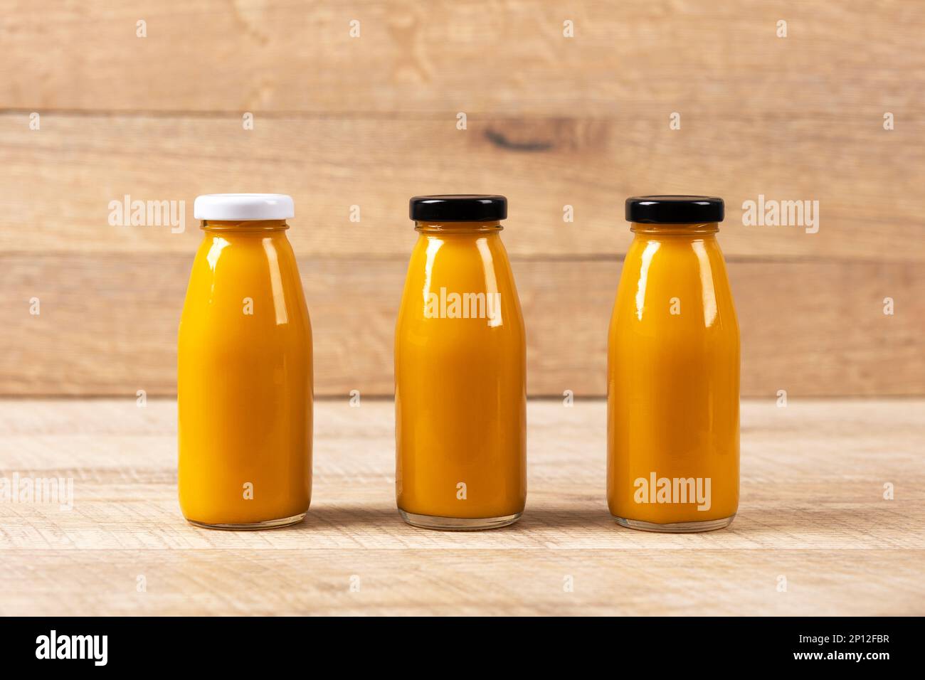 Drei Ananas-Smoothies für gesundes Essen in Glasflaschen auf Holzhintergrund. Gesundes, Entgiftung und diätetisches Ernährungskonzept. Stockfoto