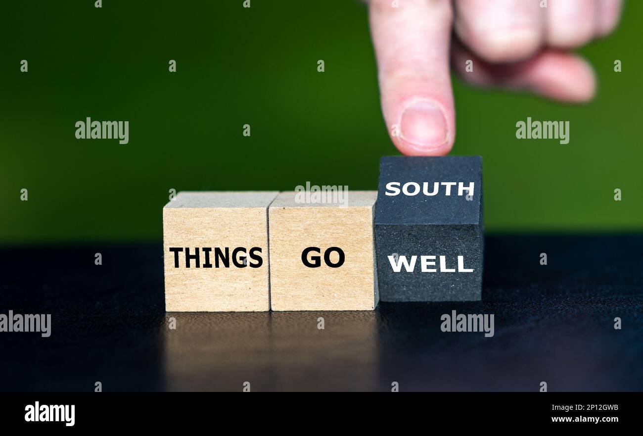 Die Hand dreht den Holzwürfel und ändert das Sprichwort „alles läuft gut“ in „alles geht nach Süden“. Stockfoto