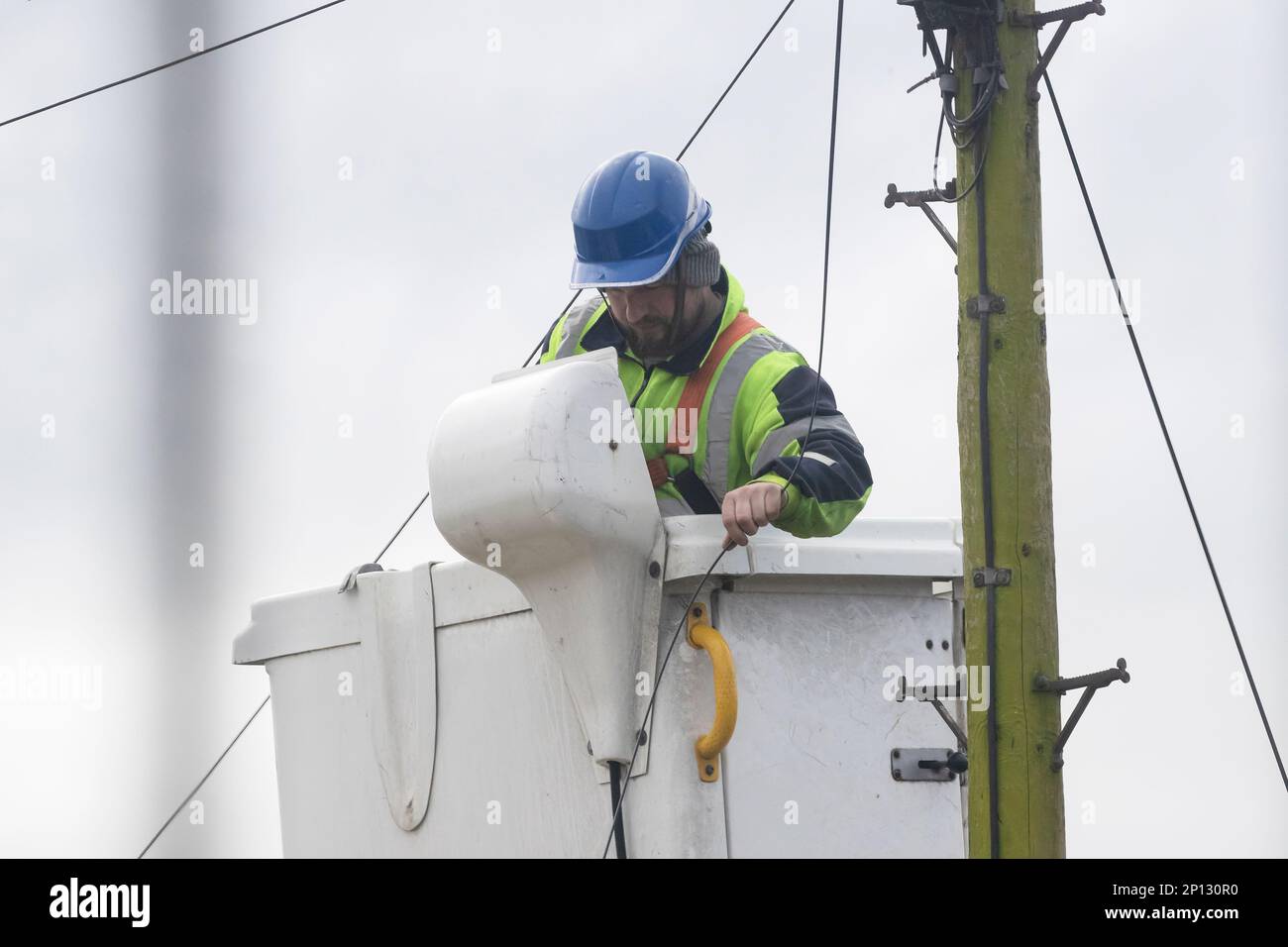 Telekommunikationsunternehmen mit entsprechender Sicherheitsausrüstung, das von einem Kirschpflücker aus arbeitet, um eine neue private Telefonleitung in West Yorkshire, Großbritannien, zu installieren Stockfoto