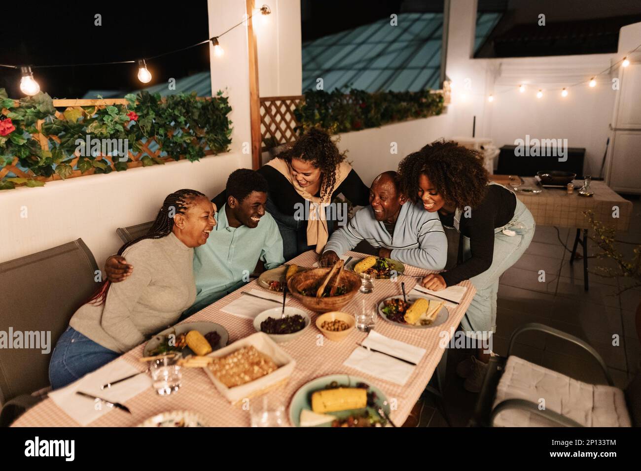 Glückliche afrikanische Familie, die zusammen auf der Terrasse des Hauses speist Stockfoto