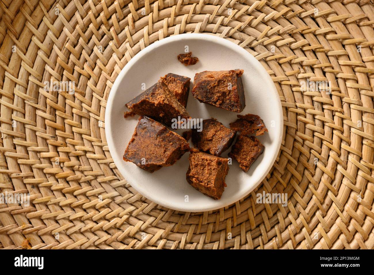 Kithul Jaggery und Treakel Natursüßer der Palme in weißer Schüssel auf traditionellem Weidenkorb. Blick von oben. Alternativer Zucker. Essen mit niedrigem GI-Wert. Super Stockfoto