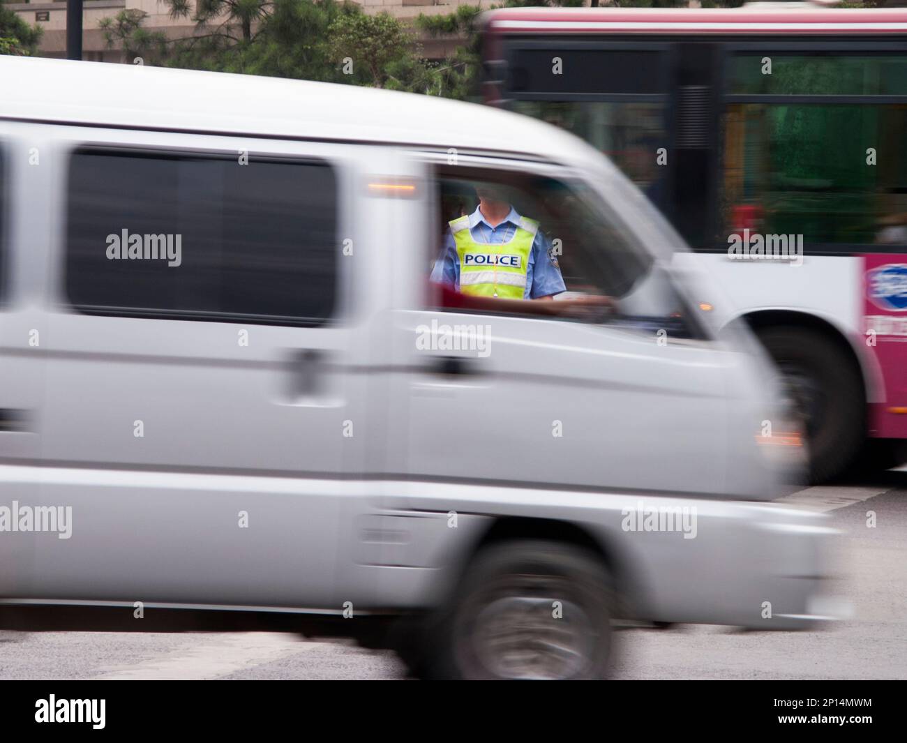 Polizist des Verkehrspolizisten an einer verkehrsreichen Kreuzung, sichtbar durch das Taxi eines vorbeifahrenden Lieferwagens, in der chinesischen Stadt Xi'an. VR CHINA. China. Führen und Anweisen von vorbeifahrenden Fahrzeugen. (125) Stockfoto