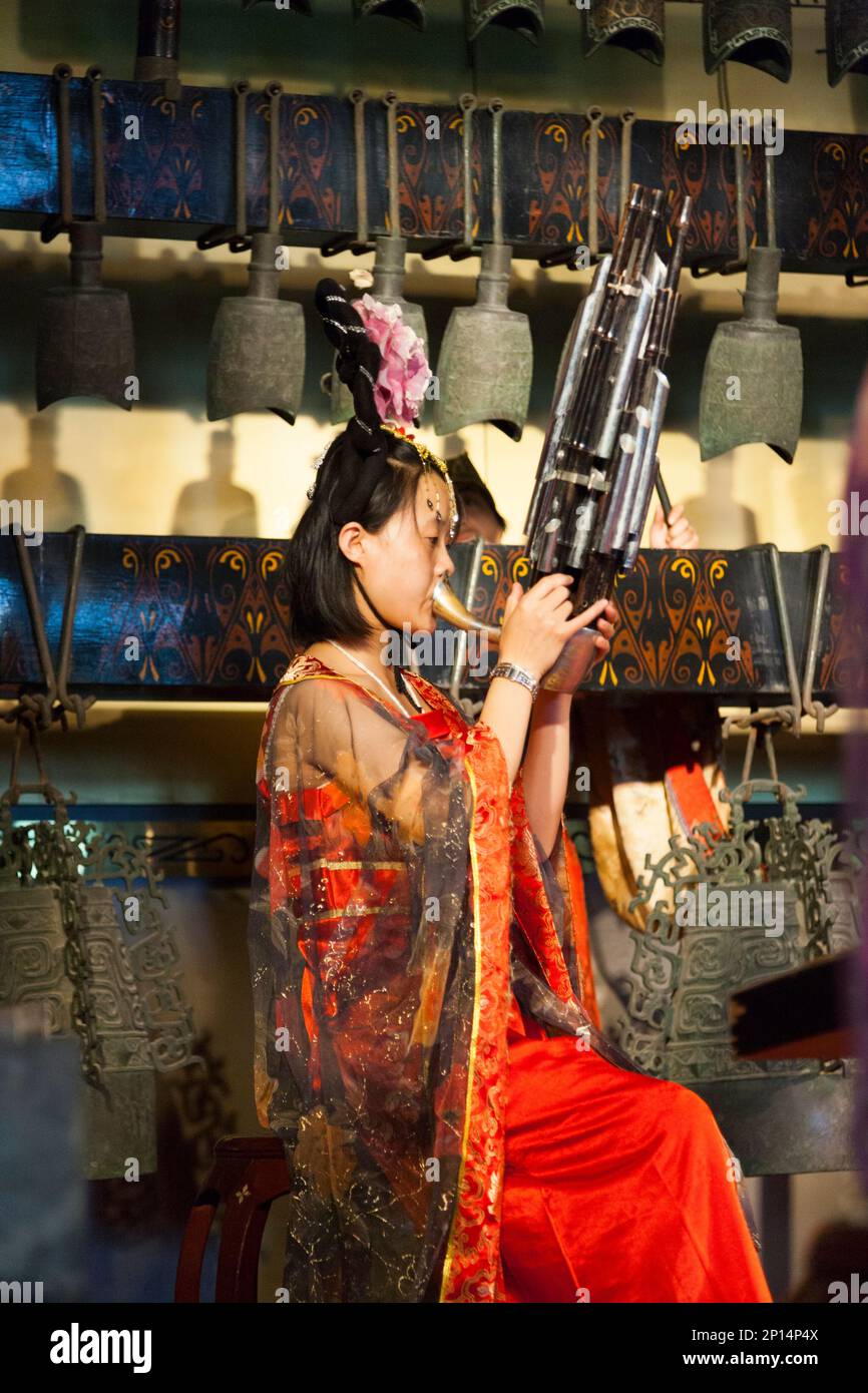 Eine Musikerin, die ein chinesisches Windinstrument spielt, vielleicht einen Sheng, im Auditorium im Glockenturm in der chinesischen Stadt Xian. VR China, China. Das 600 Jahre alte Wahrzeichen des Gebäudes ist bei Touristen beliebt, die Musikvorführungen und musikalische Darbietungen mit traditionellen chinesischen Instrumenten beobachten und hören. (125) Stockfoto
