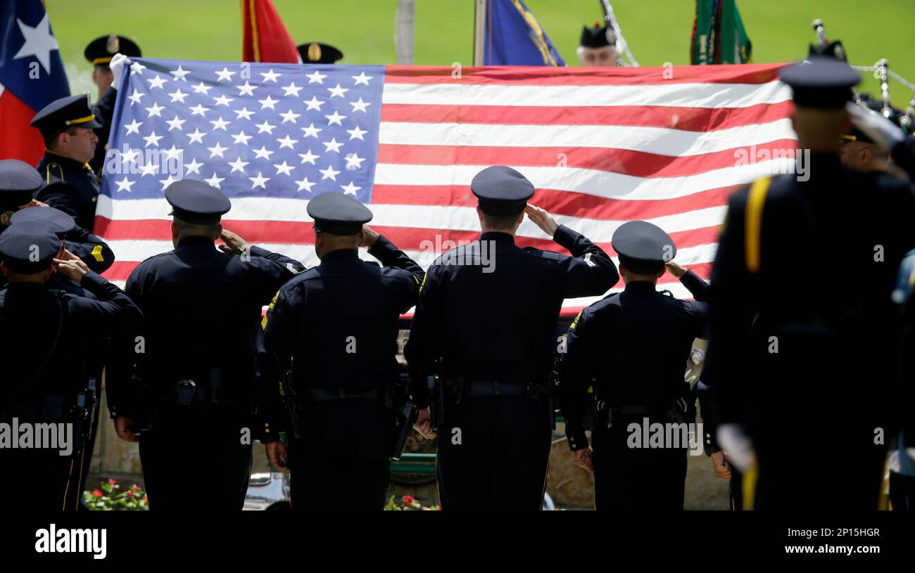 Members of an honor guard salute as the flag is lifted off of the