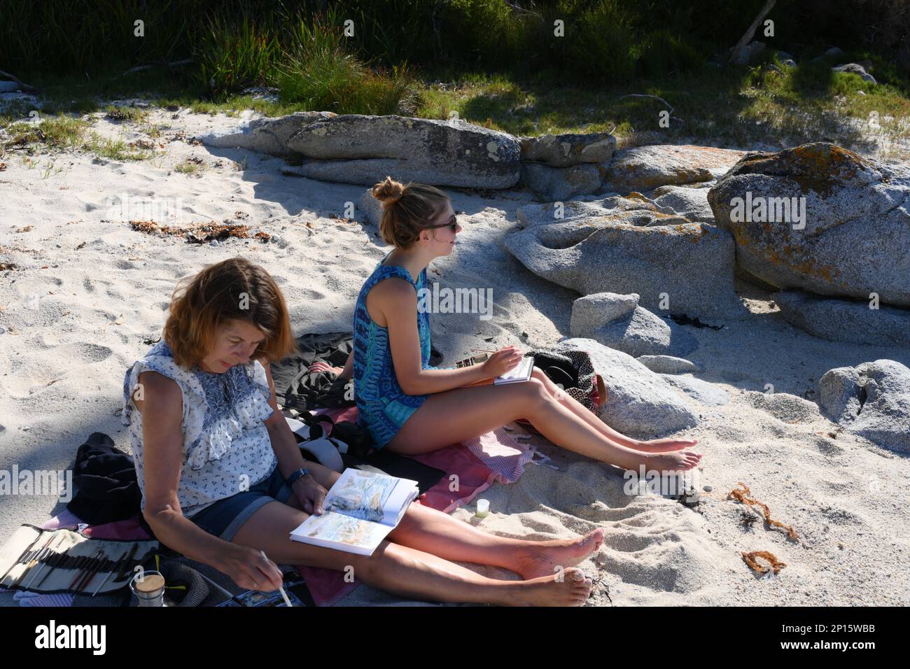 Zwei Personen an einem abgeschiedenen Strand genießen die unberührte Küste an der Skeleton Bay, Binalong, Tasmanien und nutzen die Natur als Inspiration für Malerei Stockfoto