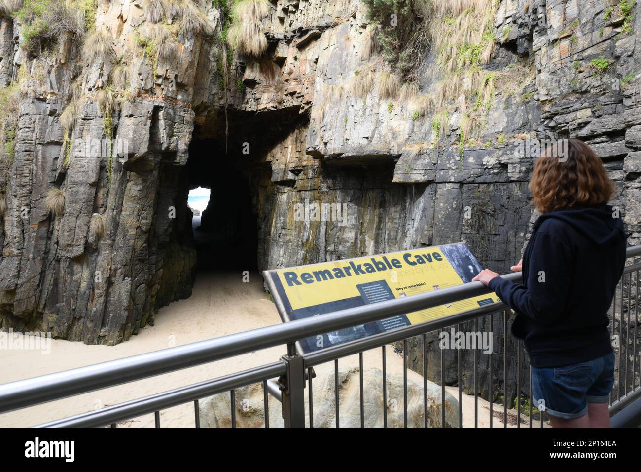 Bemerkenswerte Höhlen eine Meereshöhle unter den Klippen verbindet die Küste mit dem Meer, ausgehöhlt von Wellen. Ein Besucher sieht dieses geologische Merkmal von der Plattform aus. Stockfoto