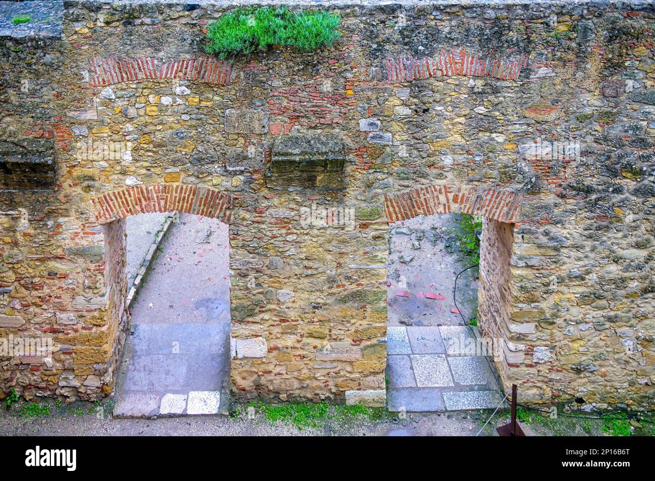 Blick aus dem hohen Winkel auf die dicke Steinmauer mit zwei Bogentüren ...
