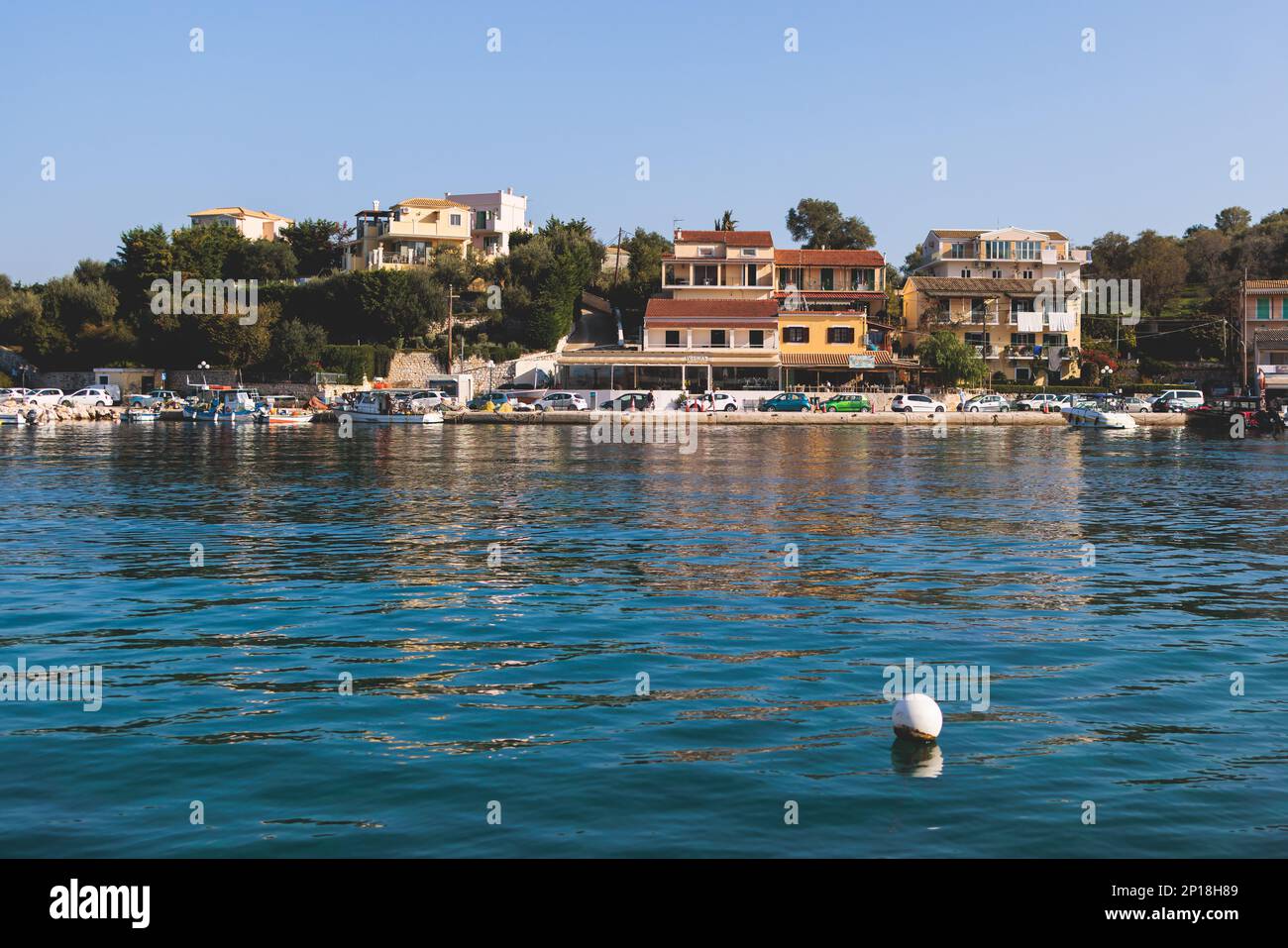 Blick aus der Vogelperspektive auf Kassiopi, Dorf an der Nordostküste der Insel Korfu, Ionische Inseln, Kerkyra, Griechenland an sonnigen Sommertagen, mit Yachthafen, Stadt, Strand und Stockfoto