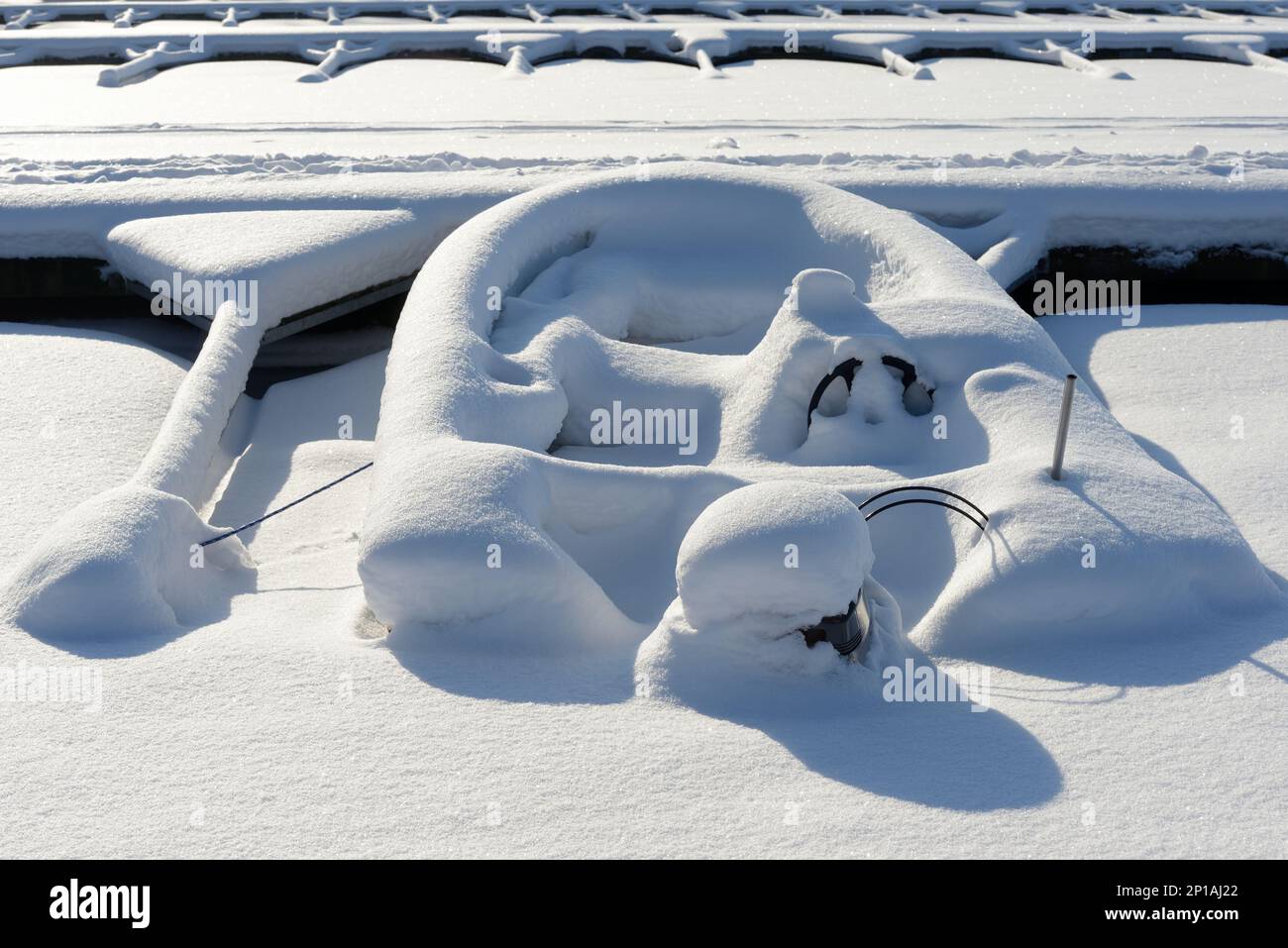 Boot mit Außenbordmotor, im Winter mit Schnee bedeckt auf dem Bootsparkplatz Stockfoto