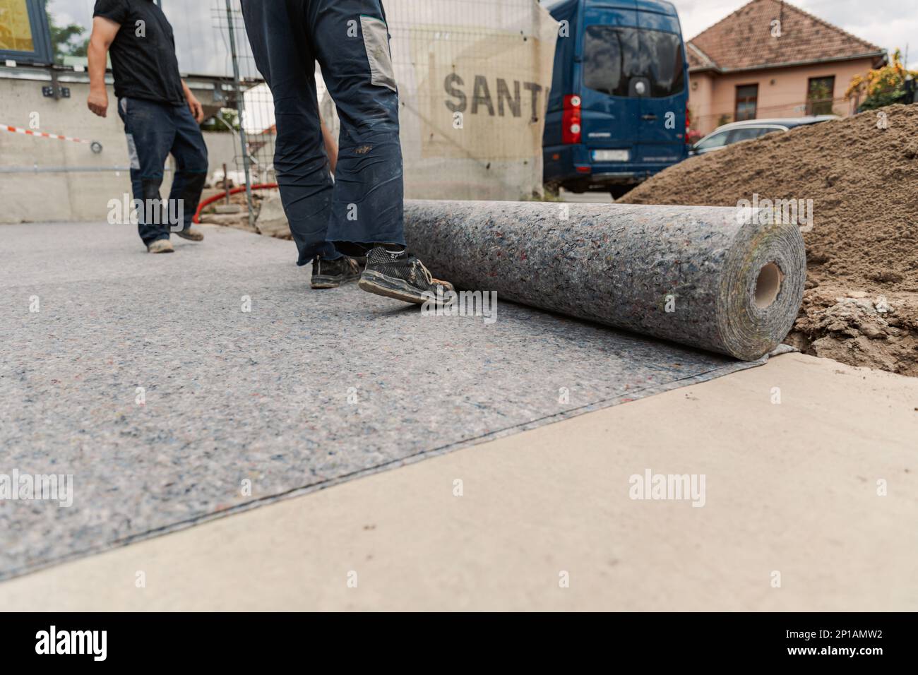 Arbeiter bereitet Geotextil für das Dach vor, bedeckt es mit synthetischer PVC-Membran Stockfoto