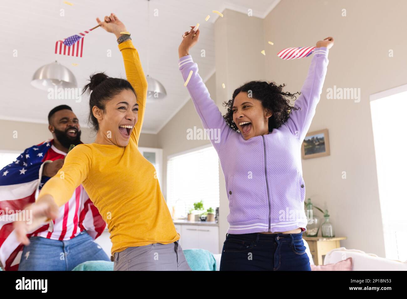 Fröhliche, vielfältige Freunde sitzen auf dem Sofa, sehen sich ein Fußballspiel an und feiern Stockfoto