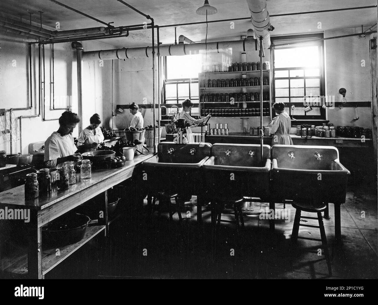 Ein Team von Leuten, die Obstkonserven mit Konservierungsmethoden in einer kommerziellen Küche zubereiten, ca. 1920, USA Stockfoto