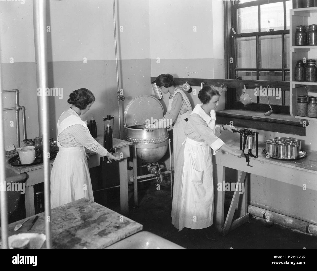 Ein Team von Leuten, die Obstkonserven mit Konservierungsmethoden in einer kommerziellen Küche zubereiten, ca. 1920, USA Stockfoto