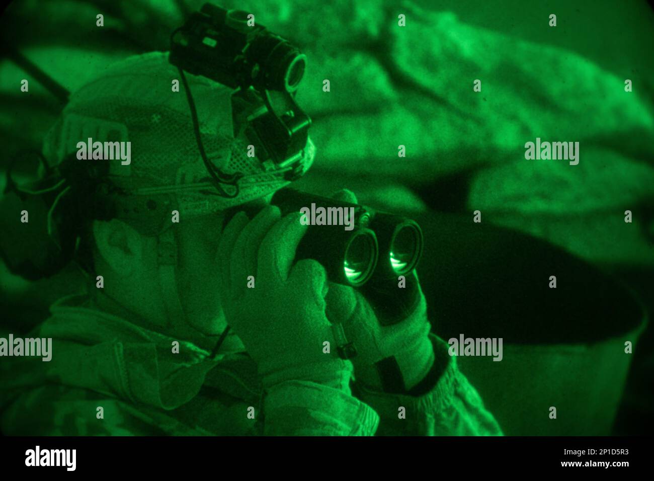 USA Armeedienst Evan Wright, der Alpha-Kompanie zugewiesen, 1. Bataillon, 125. Infanterie-Regiment, 37. Infanterie-Brigaden-Kampfteam, kombinierte gemeinsame Task Force - Operation inhärent Resolve, benutzt Ferngläser an einem Beobachtungsposten, Luftwaffenstützpunkt Al Asad, Irak, 3. Januar 2023. Stockfoto